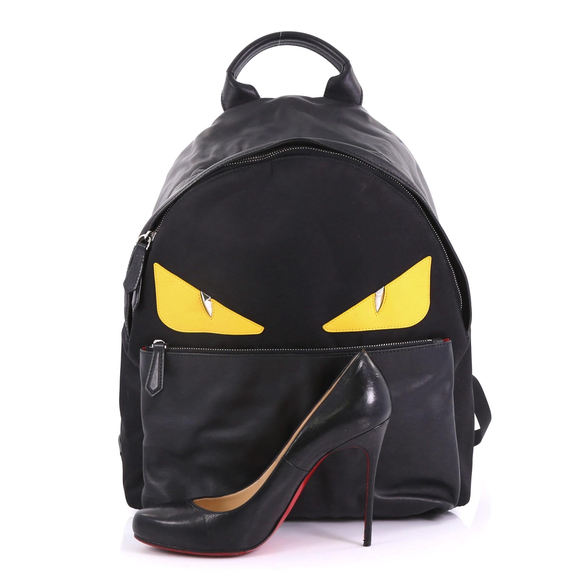 This Fendi Monster Backpack Nylon Large, crafted from black nylon and leather, features monster eye applique design, flat top handle, padded adjustable shoulder straps, exterior front zip pocket, and silver-tone hardware. Its two-way zip closure