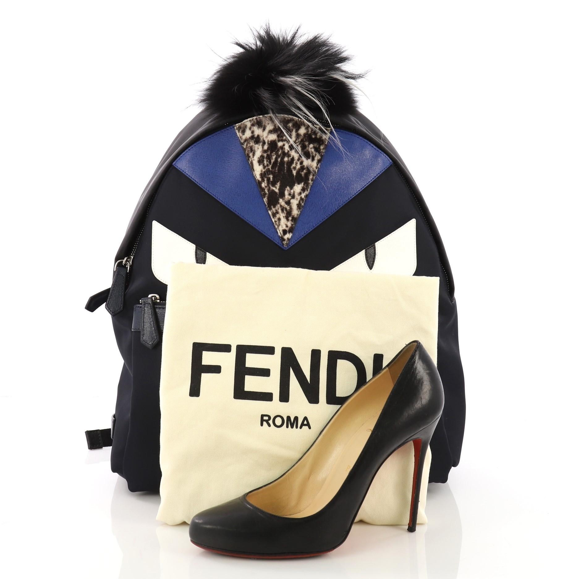 This Fendi Monster Backpack Nylon with Leather and Fur Medium, crafted from navy nylon, features Fendi's popular monster design in leather and fur accents, a flat top handle, adjustable shoulder straps, exterior front zip pocket, and silver-tone