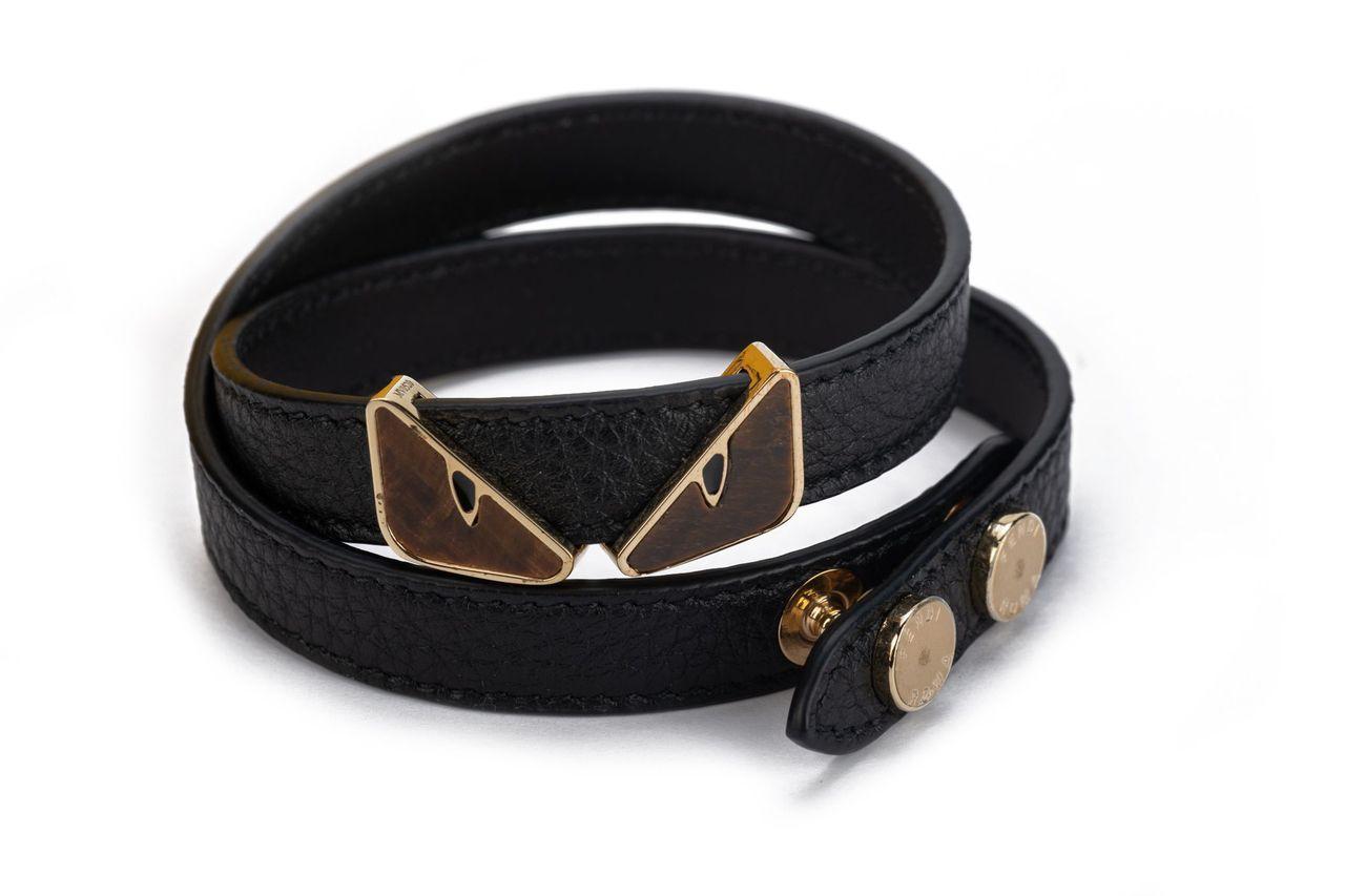 Fendi Monster double bracelet in black. The item is crafted of leather and features two Monster eyes in tiger eye stone in the middle as well as two gold buttons to close the belt. It is new and comes with a box.
