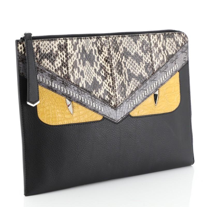 This Fendi Monster Clutch Leather with Python and Crocodile Medium, crafted from black leather with genuine python and genuine crocodile, features monster eyes motif and silver-tone hardware. Its all-around zip closure opens to a black fabric
