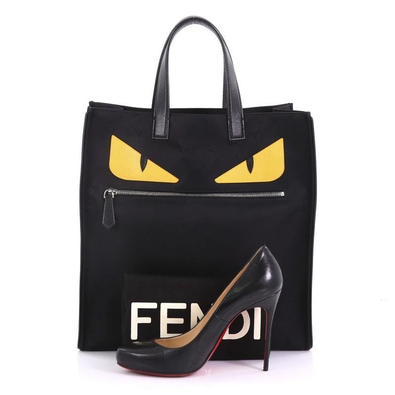 This Fendi Monster Tote Nylon, crafted from black nylon, features dual flat leather handles, monster eye applique design, front zip pocket, and silver-tone hardware. Its wide open top showcases a black nylon interior with side zip pocket. **Note: