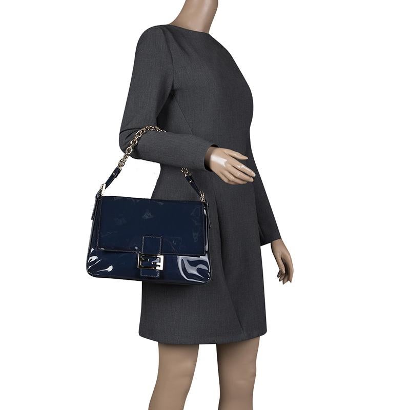 The Mama Forever shoulder bag from Fendi is an all-time classic. Accented with the striking Forever lock in gold tone on the front flap, the piece carries a patent leather exterior. A spacious suede and fabric interior and a chain handle complete