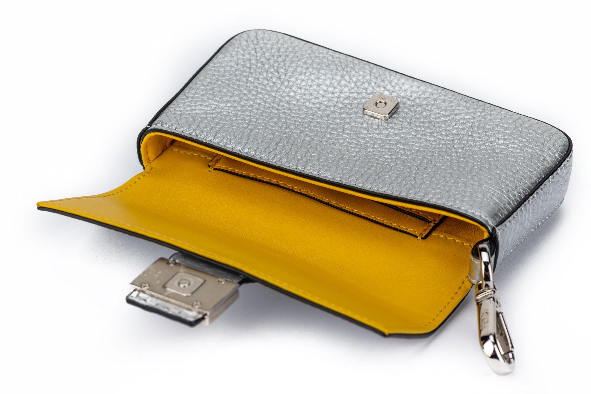 Fendi new in box silver leather fendi micro baguette with yellow interior and palladium hardware .
Can also be worn as a charm on a bigger bag or as a fanny pack on a belt .
Comes with original dustcover and box.