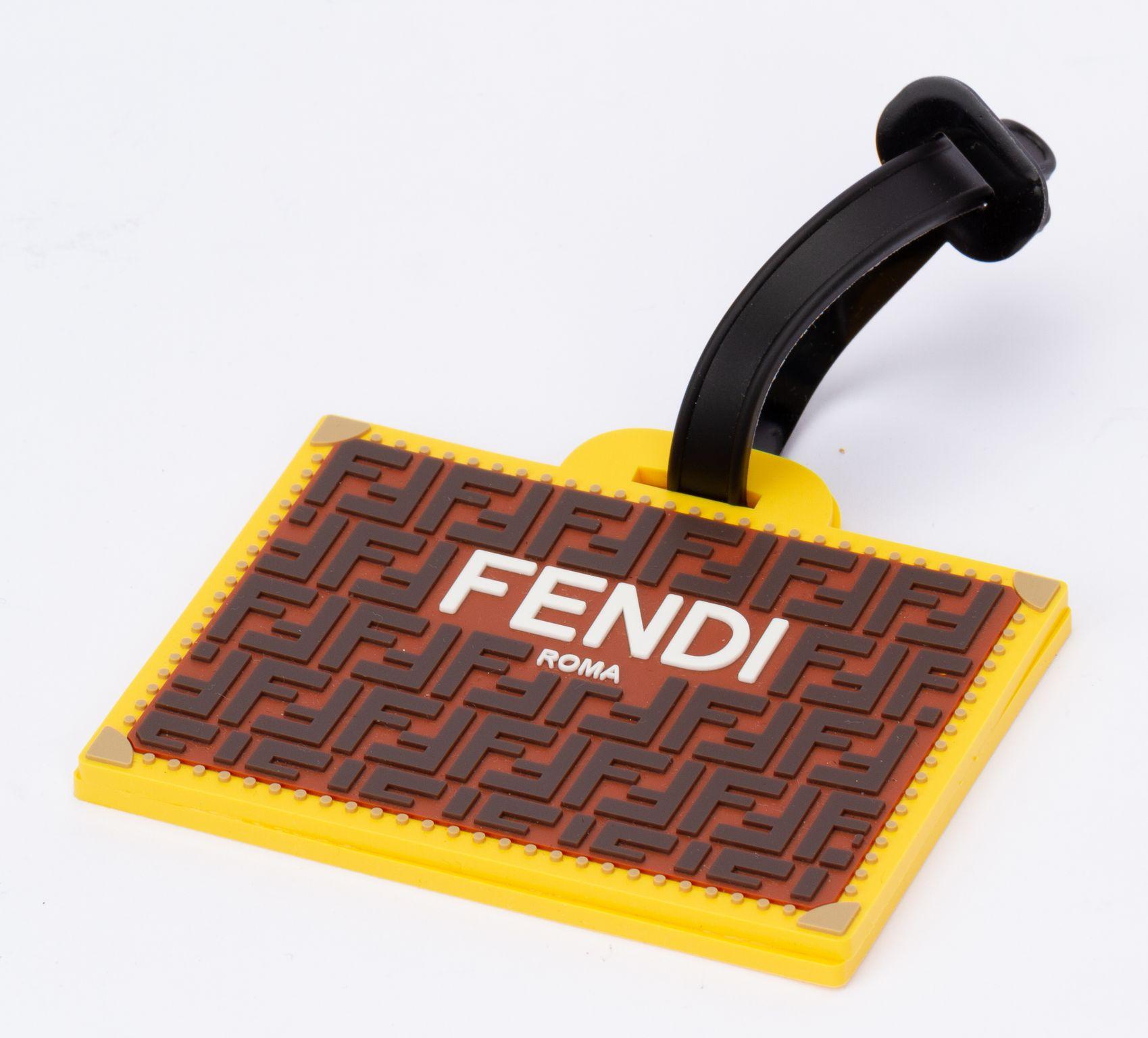 Fendi luggage tag made of silicon. On the front of the tag Fendi is written on a FF pattern in orange and brown. On the bag it's see thru and an information card is shown. The piece is new and it comes in a original dust cover.