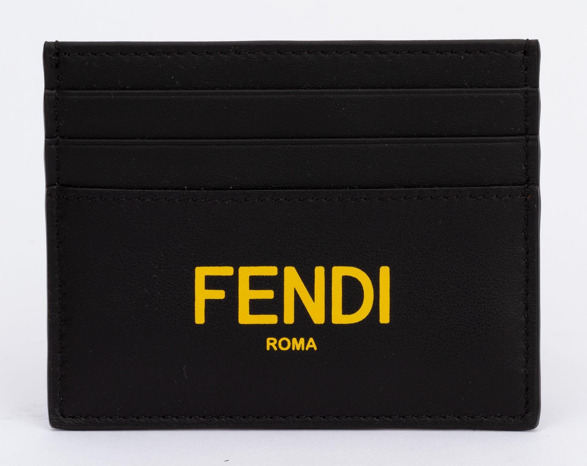 Fendi leather wallet in black. On the front Fendi is written in a bright yellow. The holder comes with 6 card departments. It is new and includes tag, booklet, original box and dust cover.