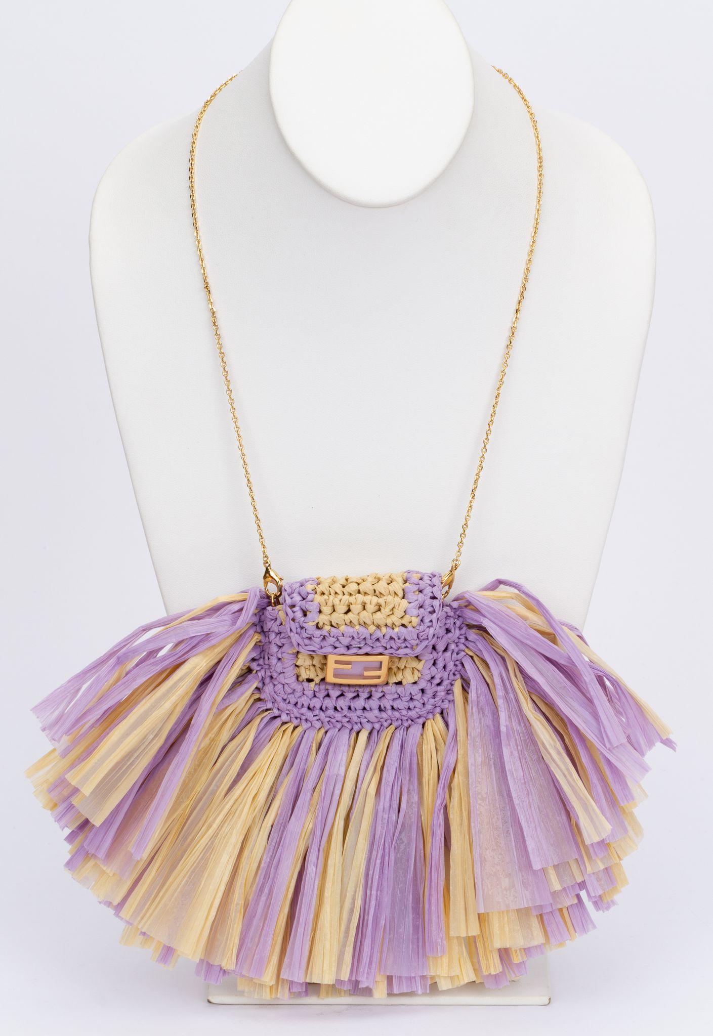 Fendi new in box raffia micro baguette tassel necklace. The center piece of the necklace is a mini Fendi knitted bag on which are multiple tassels in yellow and purple attached. The necklace chain is adjustable and detachable (drop up to 21