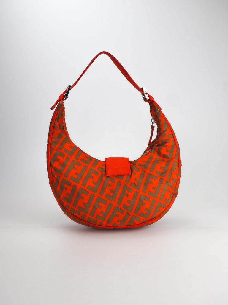 This croissant shaped Fendi bag is made with orange nylon with leather trim. The bag features a fold over flap with a logo buckle and snap fastening, top zip closure, a flat leather shoulder strap, yucca monogram print thorughout and an organ nylon