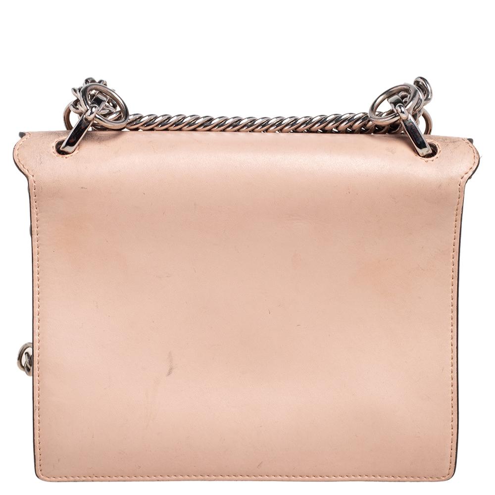 This stunning Kan I bag by Fendi has been crafted in Italy and will elevate your look instantly. It is made of leather and comes in a peach hue. With a sturdy silhouette, this bag is adorned with an embroidered & studded flap and a stud lock that