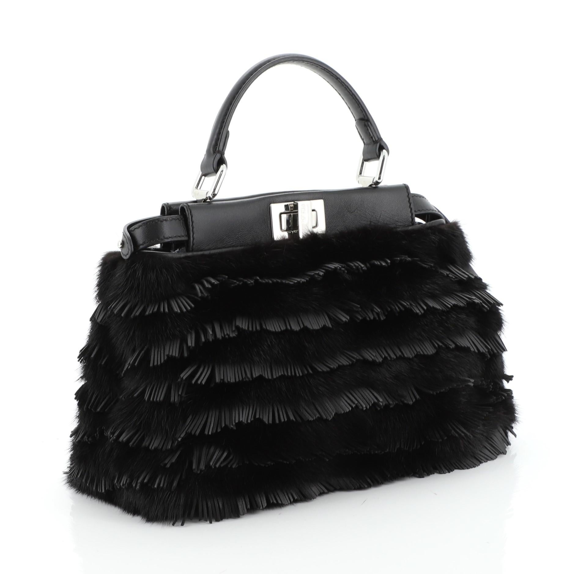 This Fendi Peekaboo Bag Fringe Leather Mini, crafted from black fringe leather, features short leather top handle, protective base studs, and silver-tone hardware. Its two compartments with turn-lock and zip closures open to a black leather interior