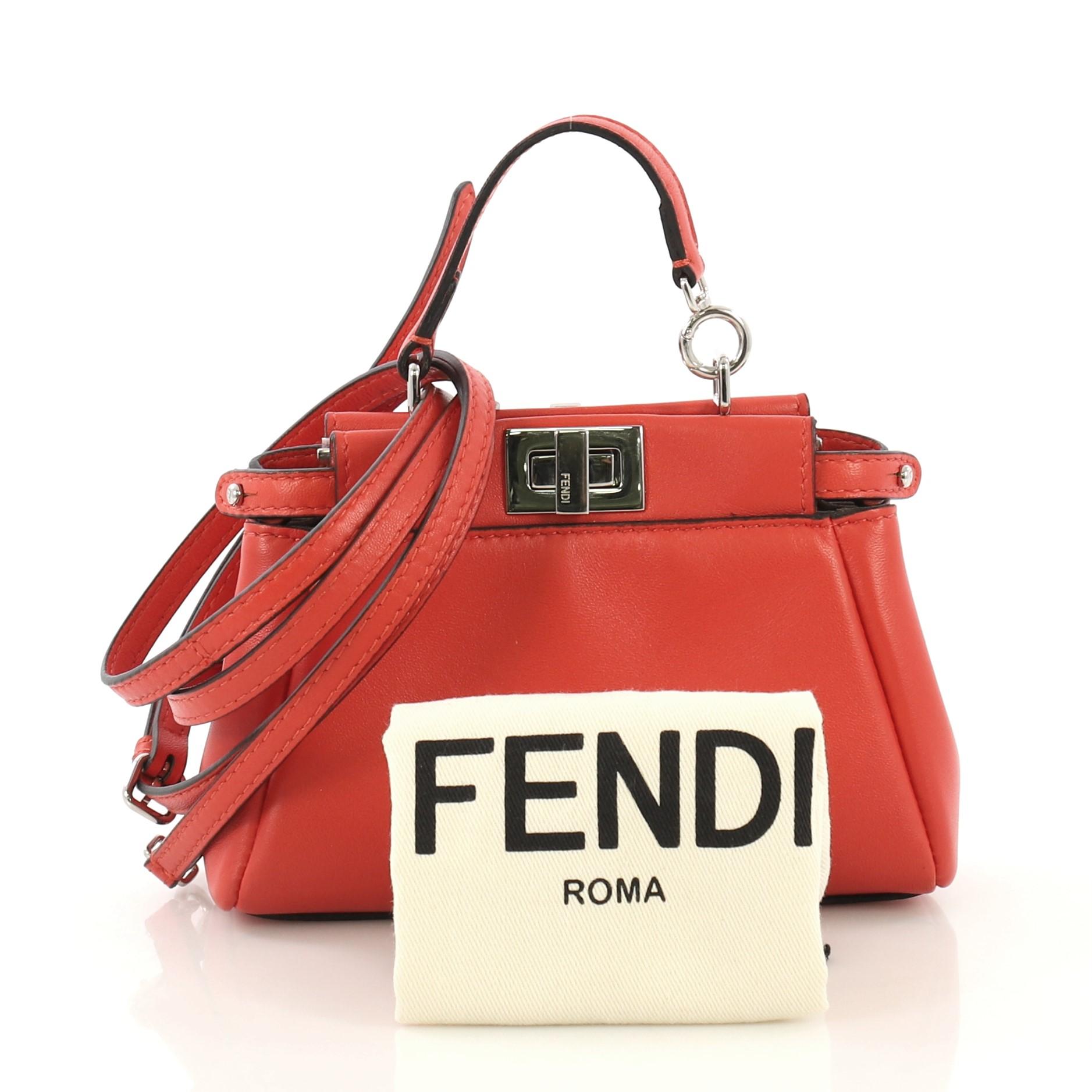 This Fendi Peekaboo Bag Leather Micro, crafted from red leather, features a top frame silhouette, flat leather handle, dual compartments with turn-lock and snap closures, and silver-tone hardware. It opens to a gray microfiber interior with side