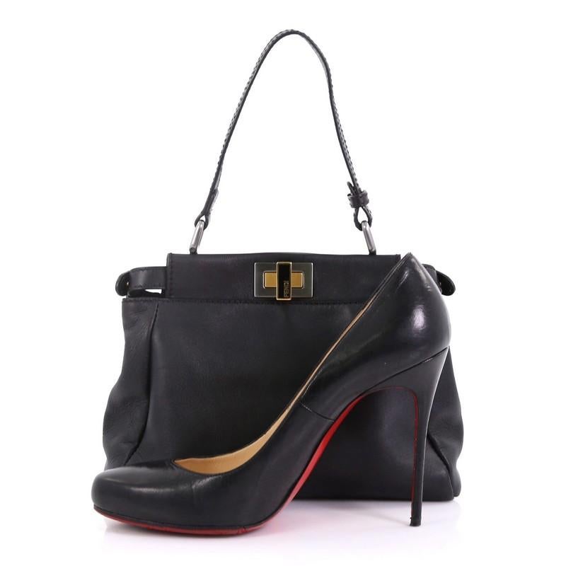 This Fendi Peekaboo Bag Leather Mini, crafted from black leather, features a leather top handle and silver and gold-tone hardware. Its turn-lock and snap closures open to a black microfiber interior with dual compartments and side zip pocket.