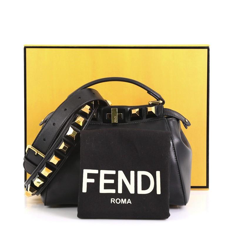 This Fendi Peekaboo Bag Leather with Studded Detail Mini, crafted in black leather , features flat leather top handle, stud detailing, and gold-tone hardware. Its turn-lock closures on both sides opens to a black leather interior with a zip pocket.