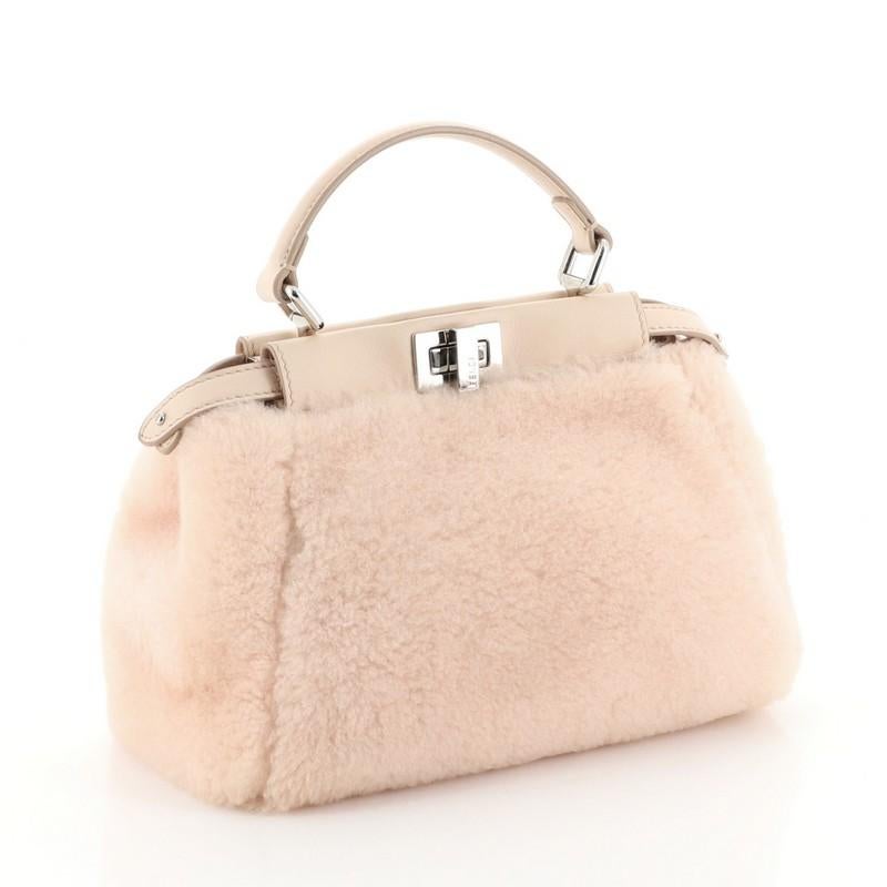 This Fendi Peekaboo Bag Shearling Mini, crafted from pink shearling, features a leather top handle and silver-tone hardware. Its turn-lock and snap closures open to a pink leather interior with dual compartments and side zip pocket. 

Estimated