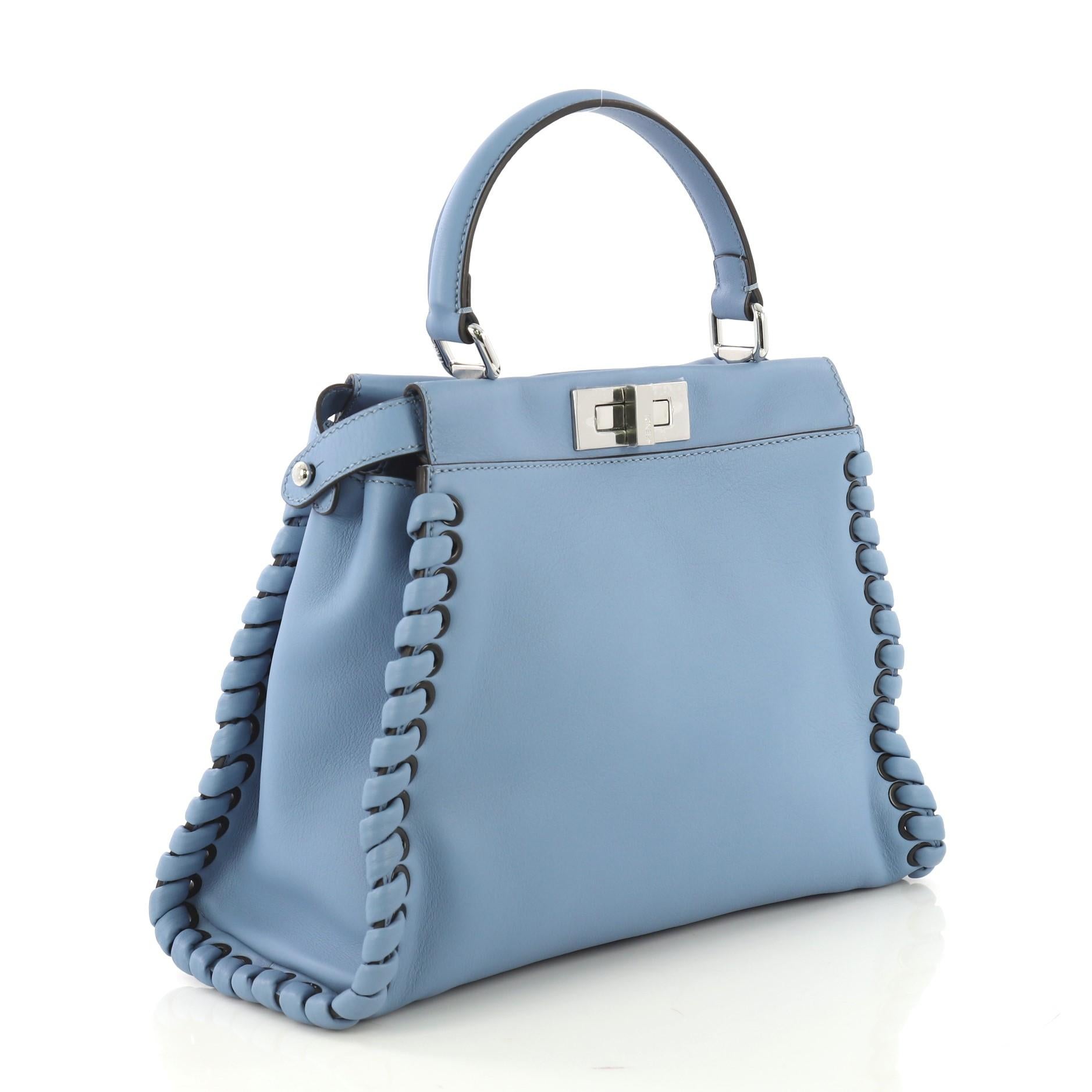 This Fendi Peekaboo Bag Whipstitch Leather Regular, crafted from blue leather, features a top frame silhouette, flat leather handle, whipstitch detailing, and silver-tone hardware. Its turn-lock and snap closures open to a black suede and blue