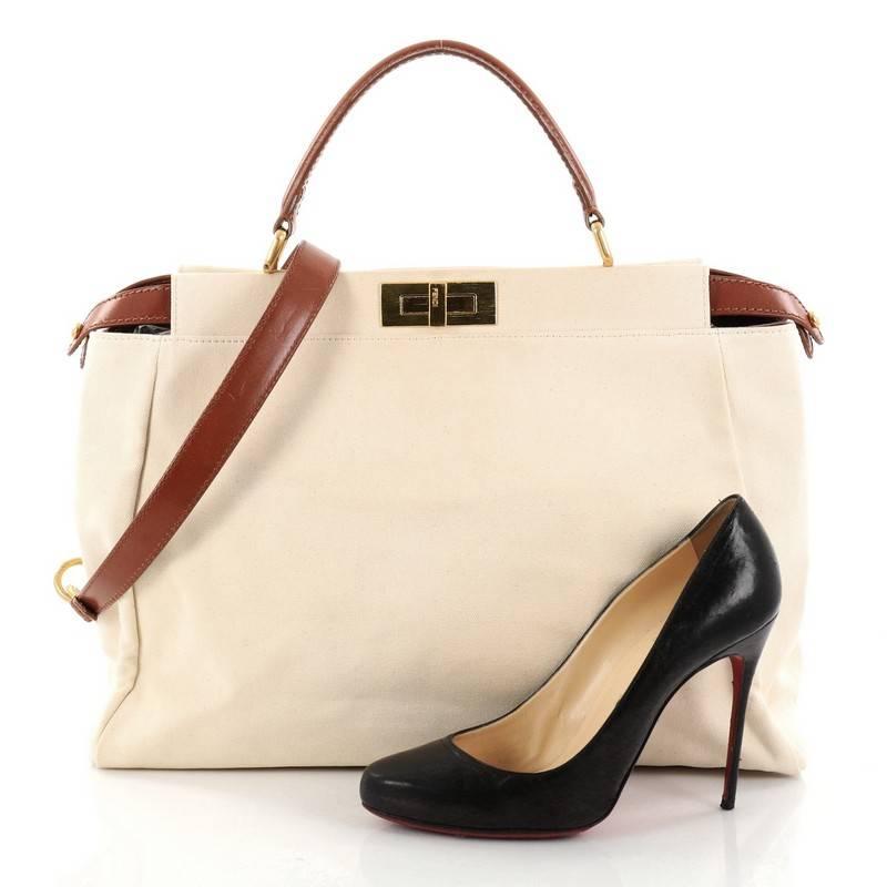 This authentic Fendi Peekaboo Handbag Canvas Large is one of Fendi's best known designs exuding a luxurious yet minimalist appearance. Crafted in off white canvas, this versatile and stylish satchel features a flat brown leather top handle,