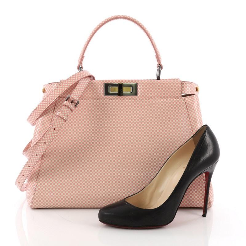 This Fendi Peekaboo Handbag Checkered Leather With Crystal Beading Interior Regular, crafted in pink checkered leather, features a flat leather top handle and matte gold and gunmetal-tone hardware. Its turn-lock closures on both sides open to a