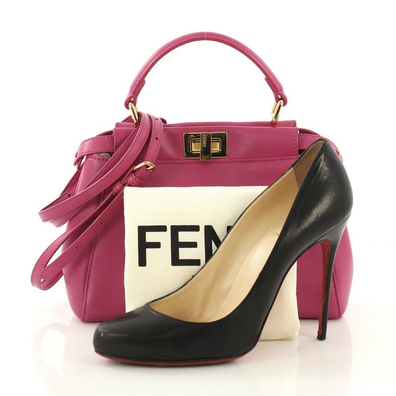 This Fendi Peekaboo Handbag Leather Mini, crafted from pink leather, features a leather top handle and gold-tone hardware. Its turn-lock and snap closures open to a pink leather interior with dual compartments and side zip pocket. **Note: Shoe