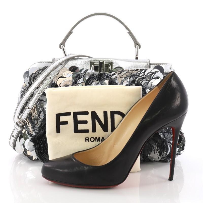 This Fendi Peekaboo Handbag Paillettes Embellished Leather Mini, crafted in paillettes embellished leather, features a flat leather top handle, protective base studs, and silver-tone hardware. Its turn-lock closures on both sides open to a metallic