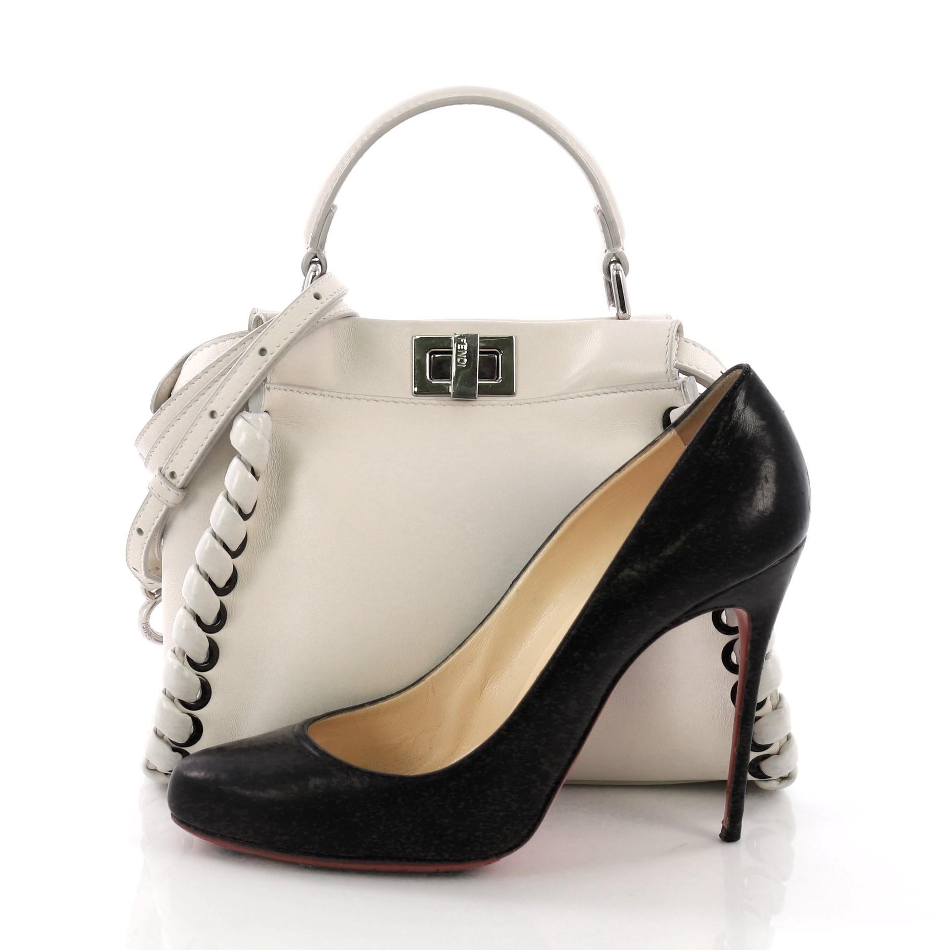 This Fendi Peekaboo Handbag Whipstitch Leather Mini, crafted from white leather with whipstitch detailing, features a top frame silhouette, flat leather handle, and silver-tone hardware. Its turn-lock and snap closures open to a white leather