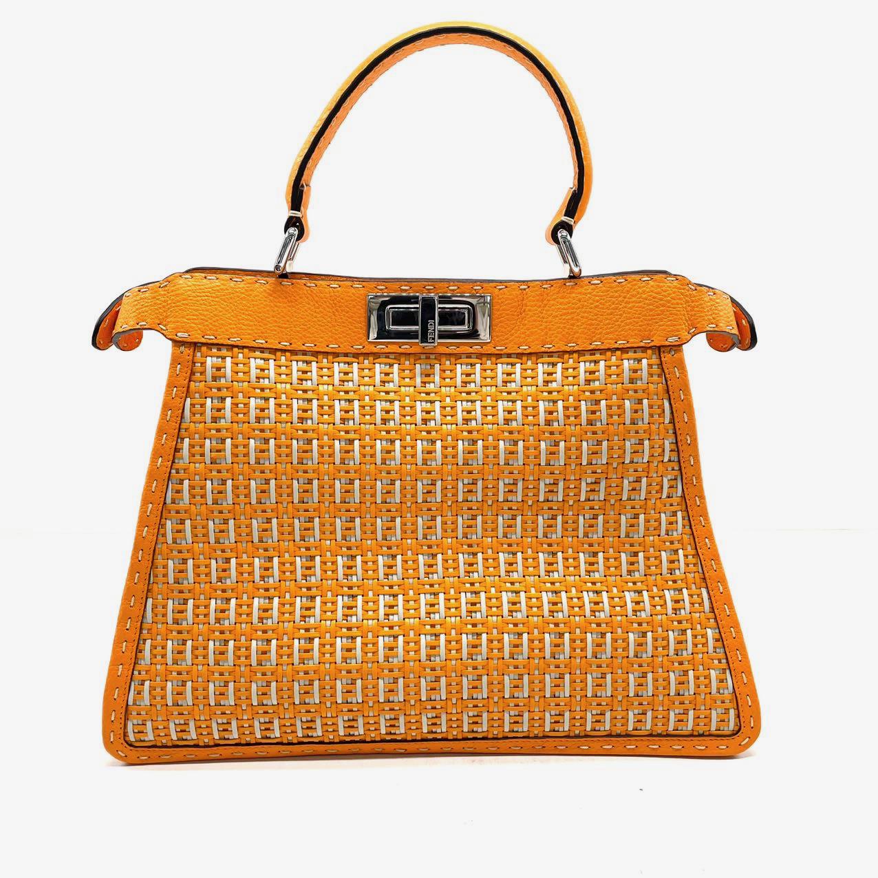 Esta edición limitada de Fendi Peekaboo está confeccionada con un intrincado entrelazado de piel naranja y blanca con un micro monograma FF, que crea la apariencia de un bolso de mimbre/rafia. Sus colores vibrantes lo convierten en el accesorio
