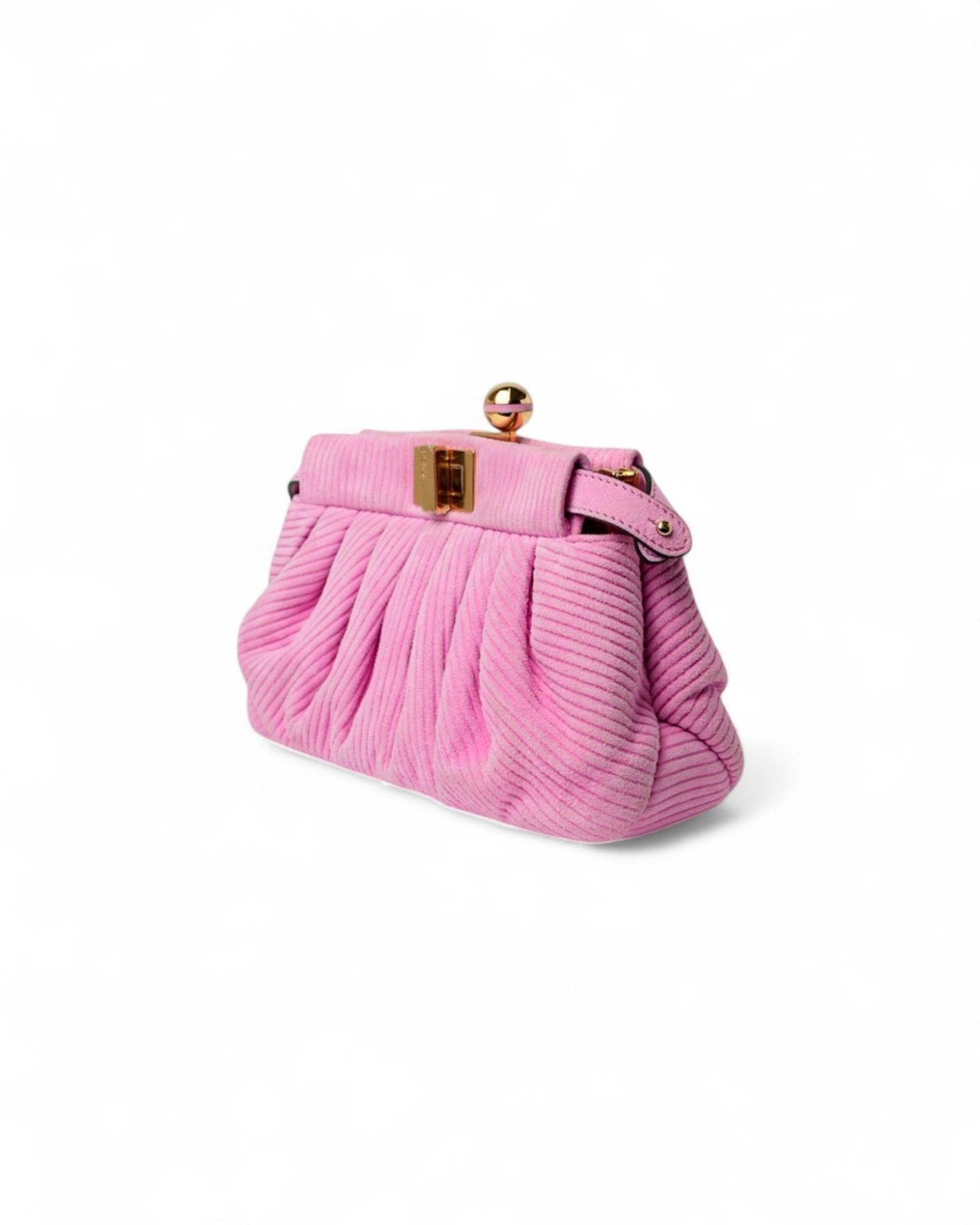 Borsa firmata Fendi, modello Lollipop nella misura small, realizzata in velluto nella colorazione rosa con hardware dorati. La borsa è dotata di una doppia chiusura a girello fronte-retro, che aggiunge praticità e stile. Internamente rivestita in