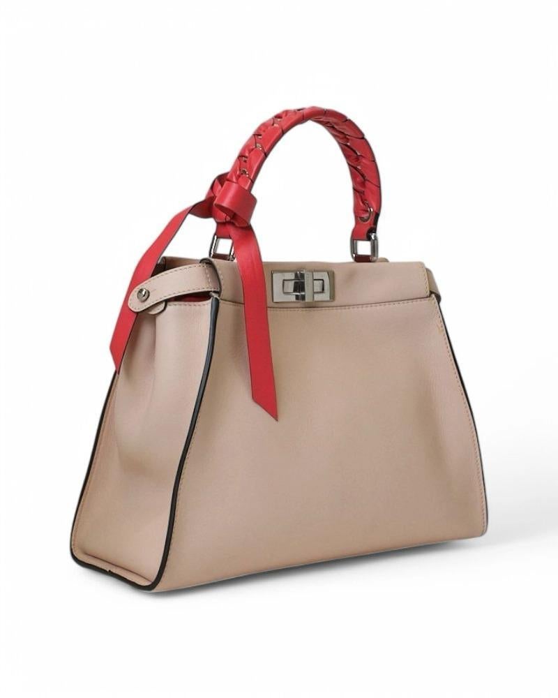 Borsa firmata Fendi, modello Peekaboo nella misura medium, realizzata in pelle rosa con inserti rossi e  hardware argentati. Dotata di una doppia chiusura a girello fronte retro, internamente rivestita in tessuto scamosciato e pelle con comode