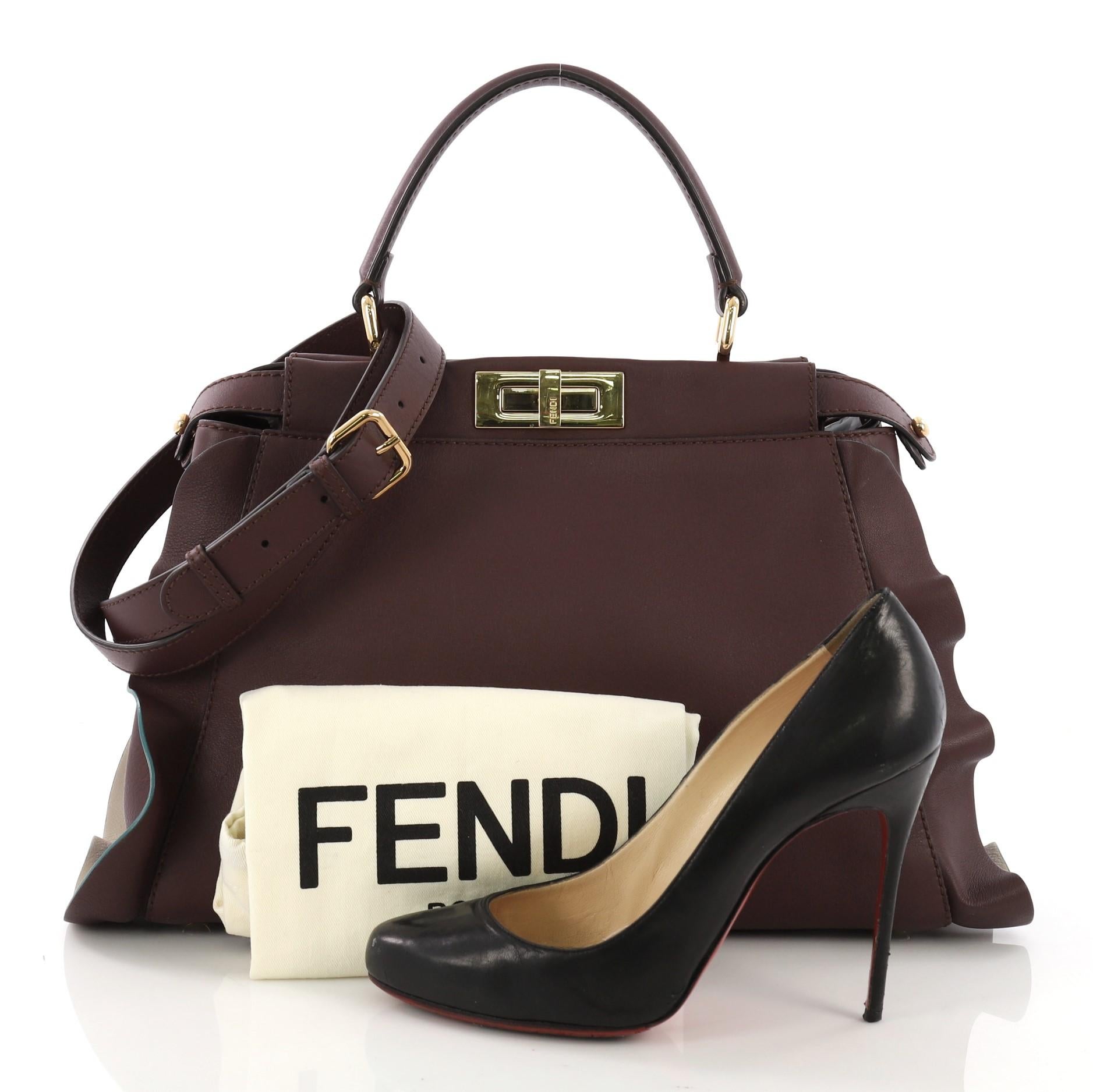 This Fendi Peekaboo Wave Handbag Leather Regular, crafted in burgundy leather, features a flat leather top handle, protective base studs, ruffled leather trim, and gold-tone hardware. Its turn-lock closures on both sides open to a burgundy leather