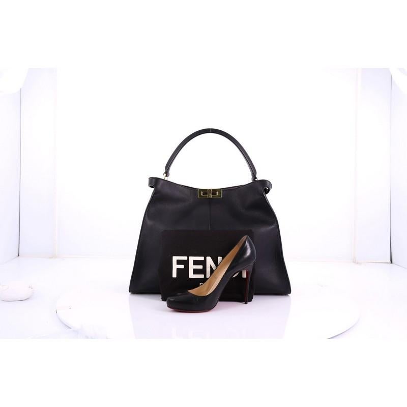 This Fendi Peekaboo X-Lite Handbag Leather Large, crafted from black leather, features a leather top handle, protective base studs, and gold-tone hardware. Its twist-lock closure opens to a brown and red leather interior with slip pocket. **Note: