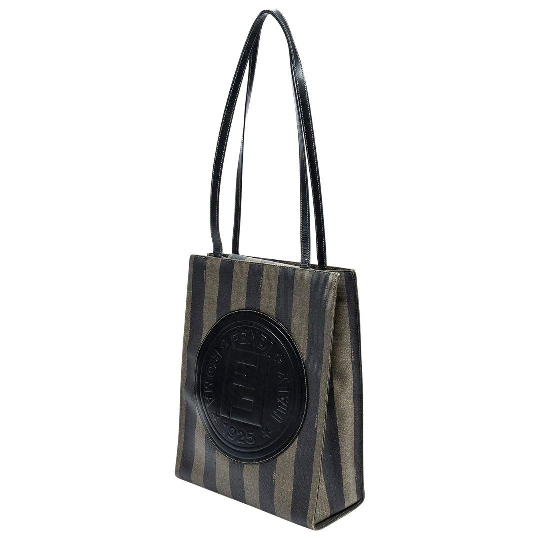 Very unusual Fendi tote crafted in striped Pequin coated canvas, with a large circular Fendi logo to the front face, and gold-tone hardware. There are two flat, long shoulder straps, and the magnetic fold over flap opens up to a fabric interior with