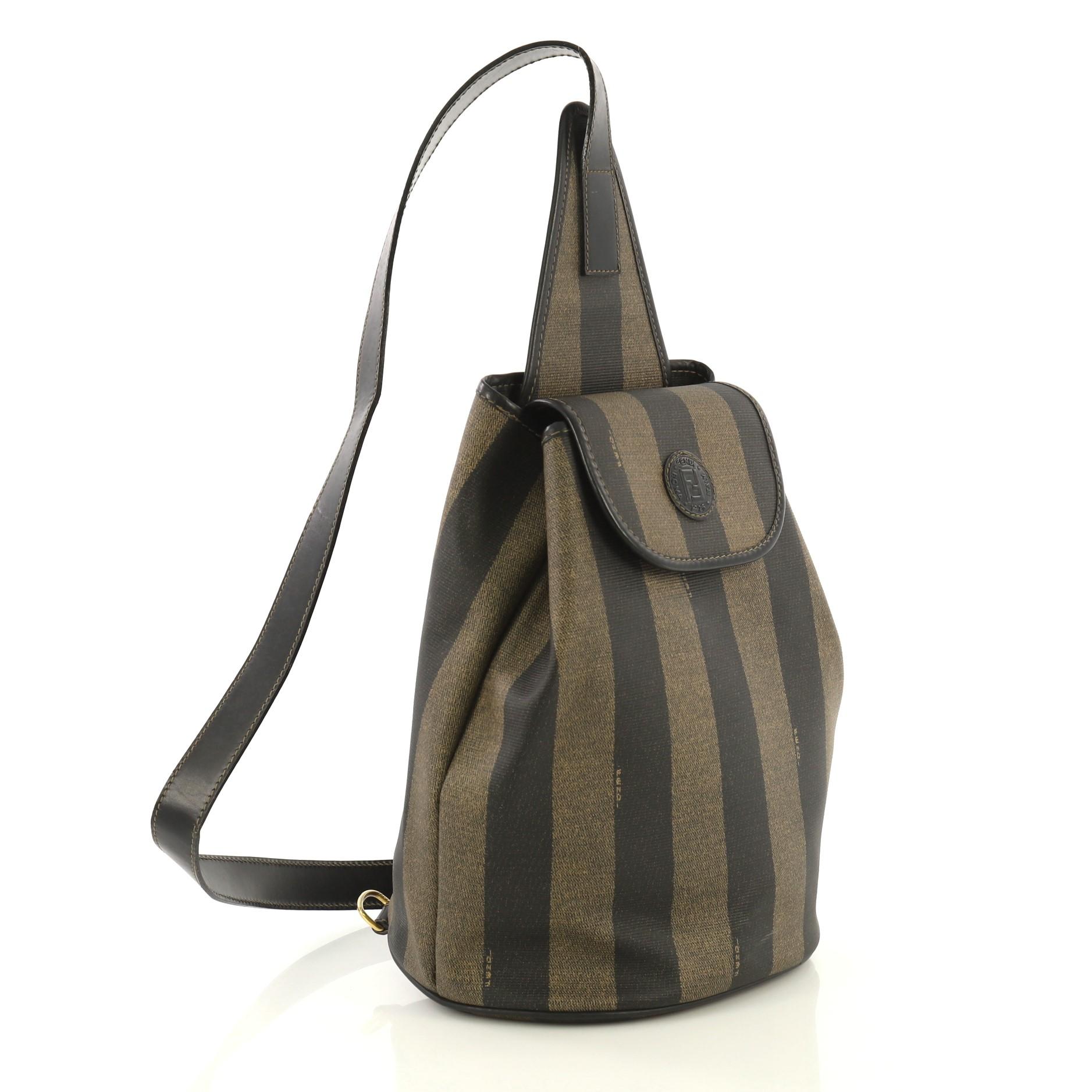 This Fendi Pequin Sling Backpack Coated Canvas Medium, crafted in black and brown coated canvas, features a leather shoulder strap and gold-tone hardware. Its flap opens to a black fabric interior with zip pocket. 

Estimated Retail Price: