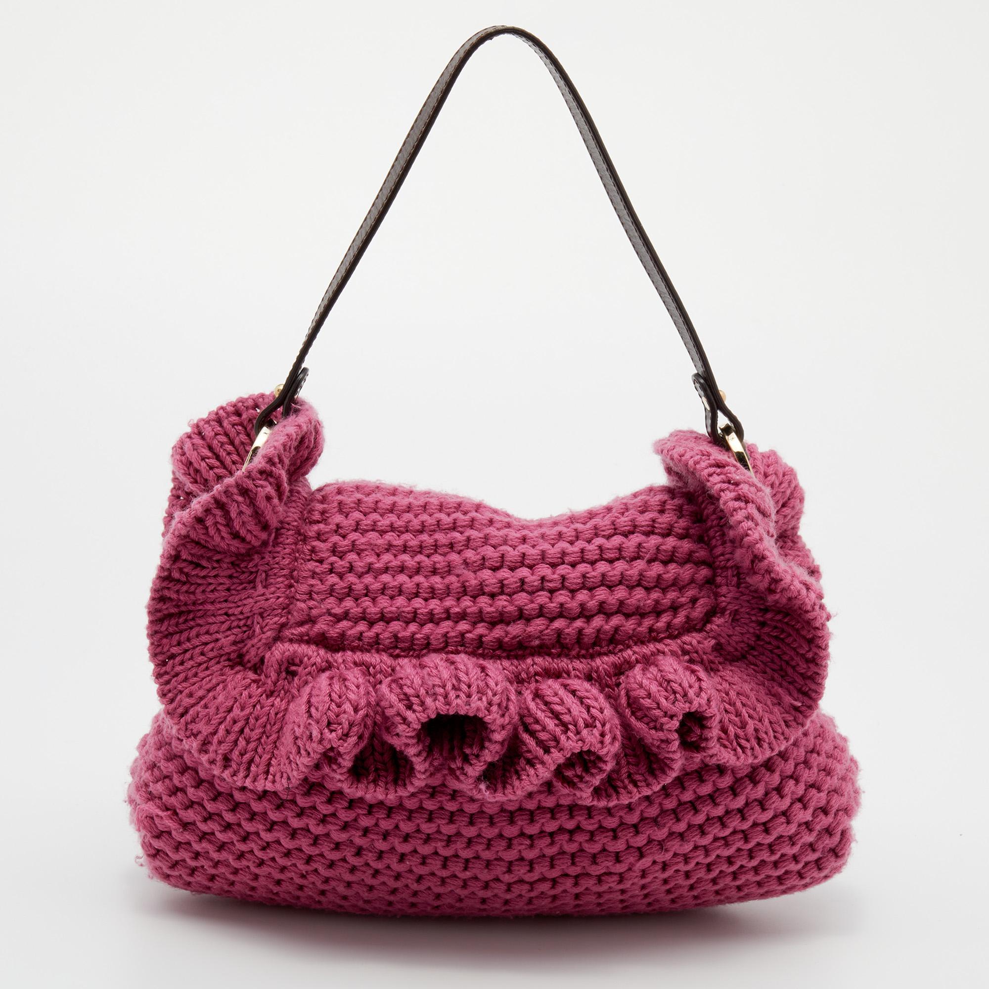 Adding a pop of color to your spring and even your winter looks, this Fendi Chef bag is stylish and effortlessly feminine. Constructed in pink knit material, this bag features a ruffle trim along with a gold-tone Fendi cutout medallion at the side