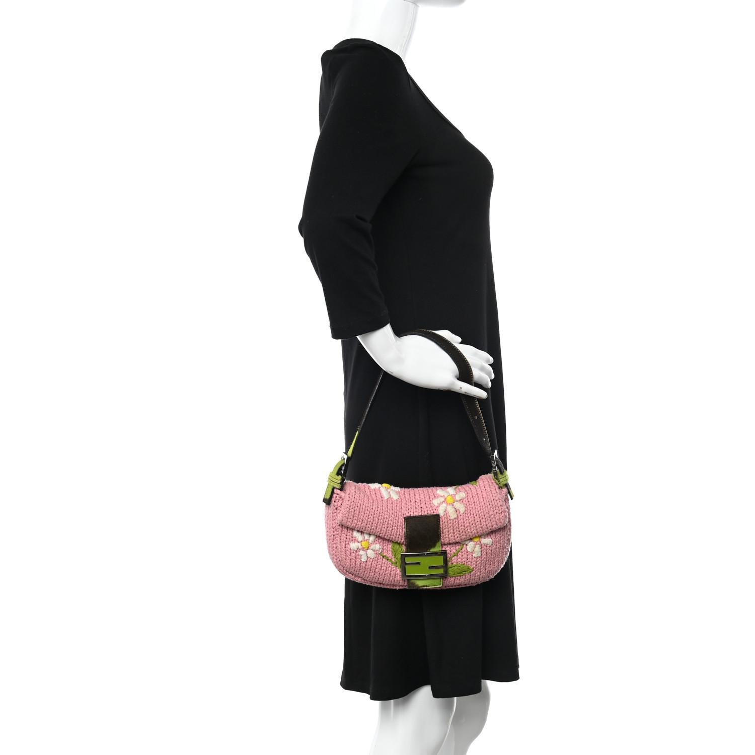 This knit baguette is made with soft pink knit and adorned with a delicate floral pattern embroidery.  The top features a leather flap with cow print, silver hardware and a magnetic snap closure. The interior has a matching pink silk satin lining