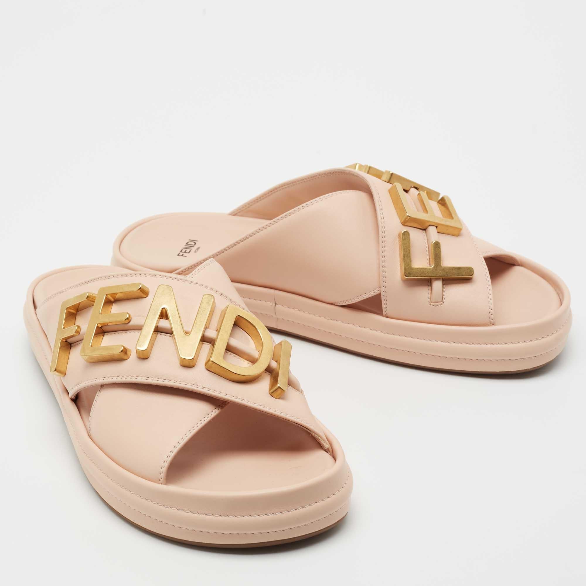 The bold lettering of 'FENDI' is balanced by leather in classy pink thus achieving a clean, put-together design you will wear for a long time. They have wide crossover straps and rubber soles.

