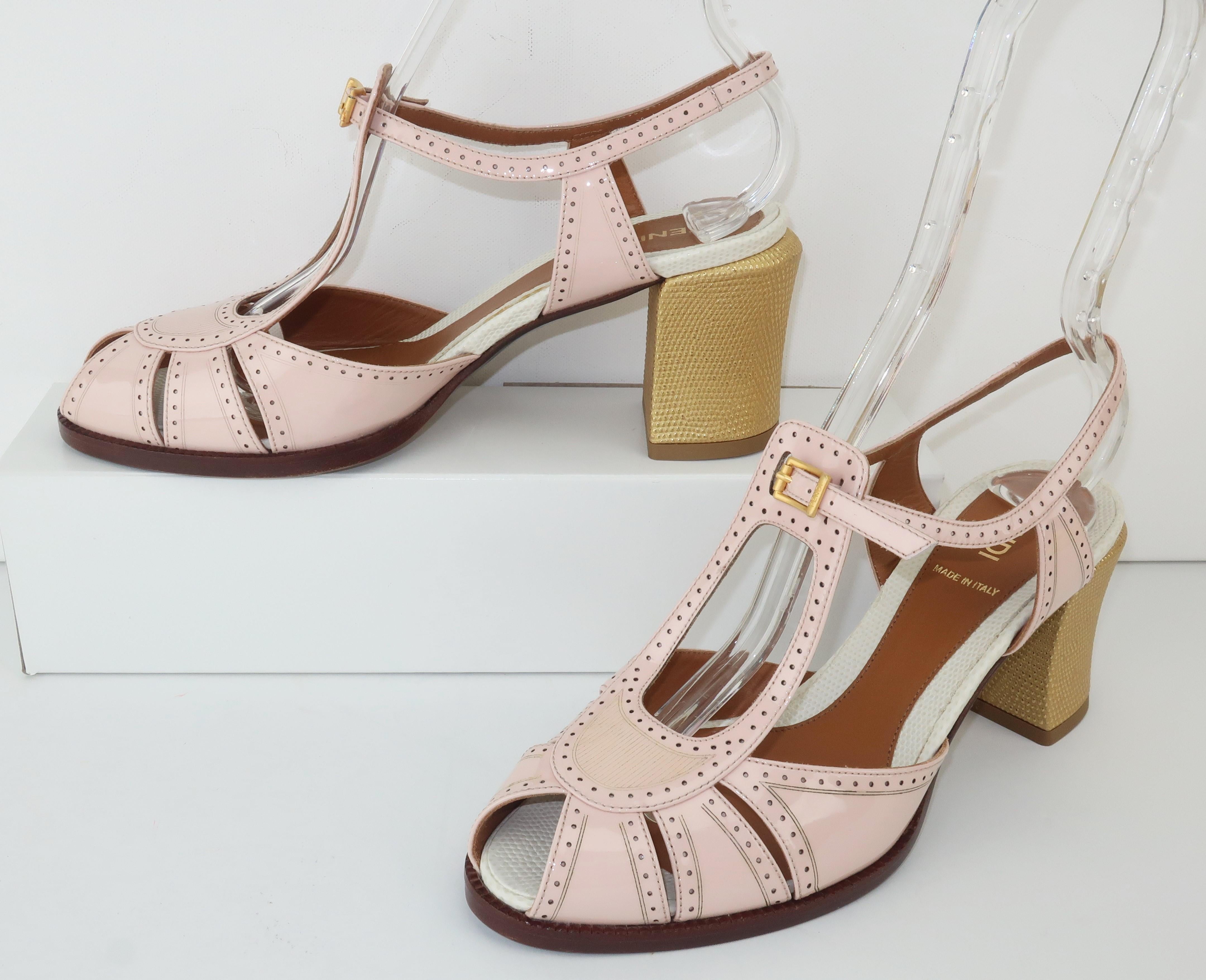 Fendi creates a peep toe t-strap sandal in pale pink patent leather with gold embossed leather heels and spectator styling reminiscent of glamorous 1930's looks. Adjustable buckle at the front and a sensible 3