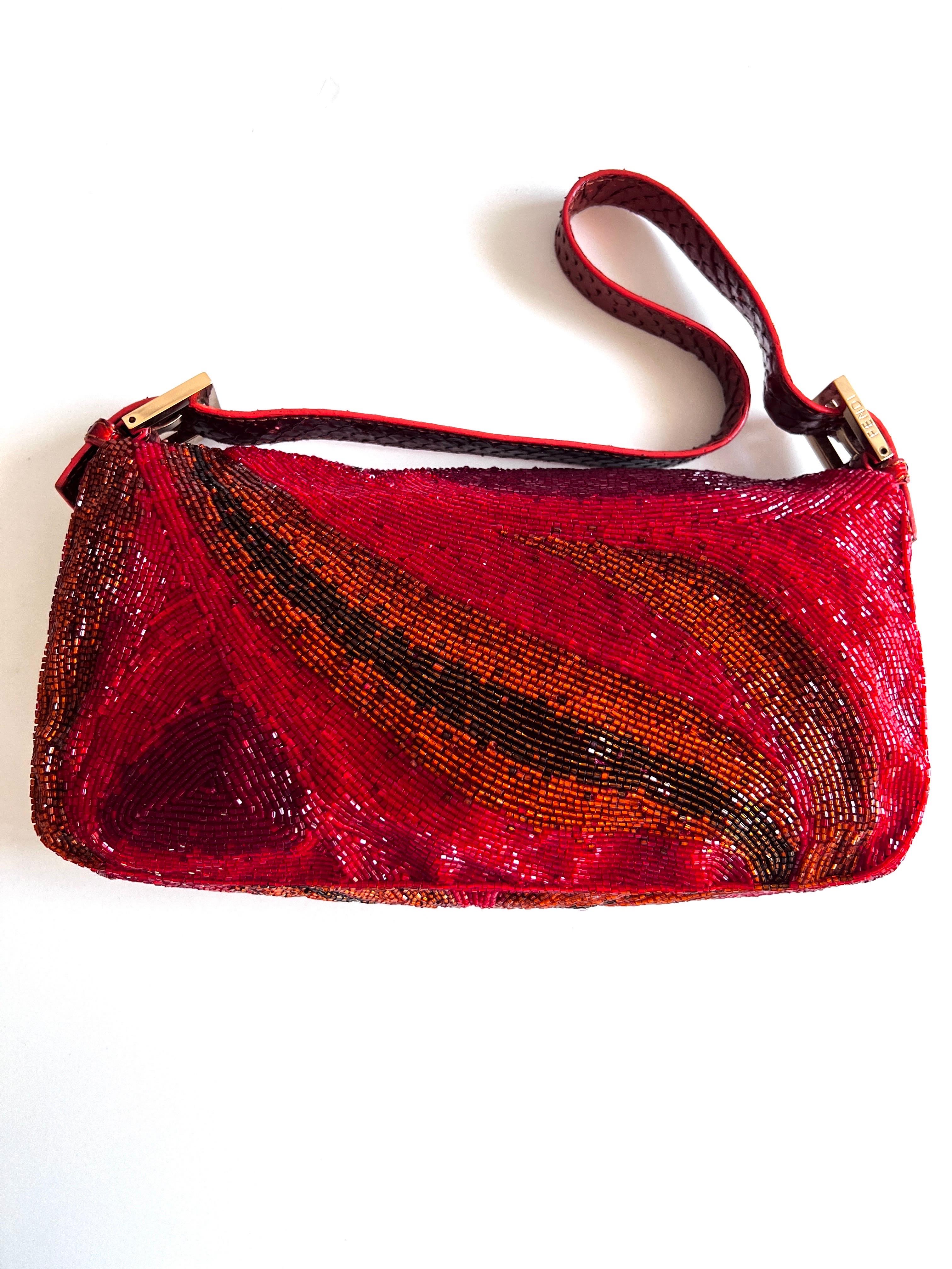 Ein seltenes Juwel in der Welt der Mode: die rote Perlen-Baguette von Fendi. Diese exquisite Handtasche, die mit Präzision und Leidenschaft gefertigt wurde, strahlt Eleganz und Raffinesse aus.

Die Baguette-Form ist mit verschlungenen roten Perlen