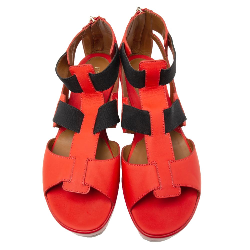 The strappy silhouette and shades of red and black make these Fendi sandals playful and fun. Crafted from leather on the exterior, they feature elastic bands, zip closures at counters, and open toes. The rubber soles and low wedge heels of the pair