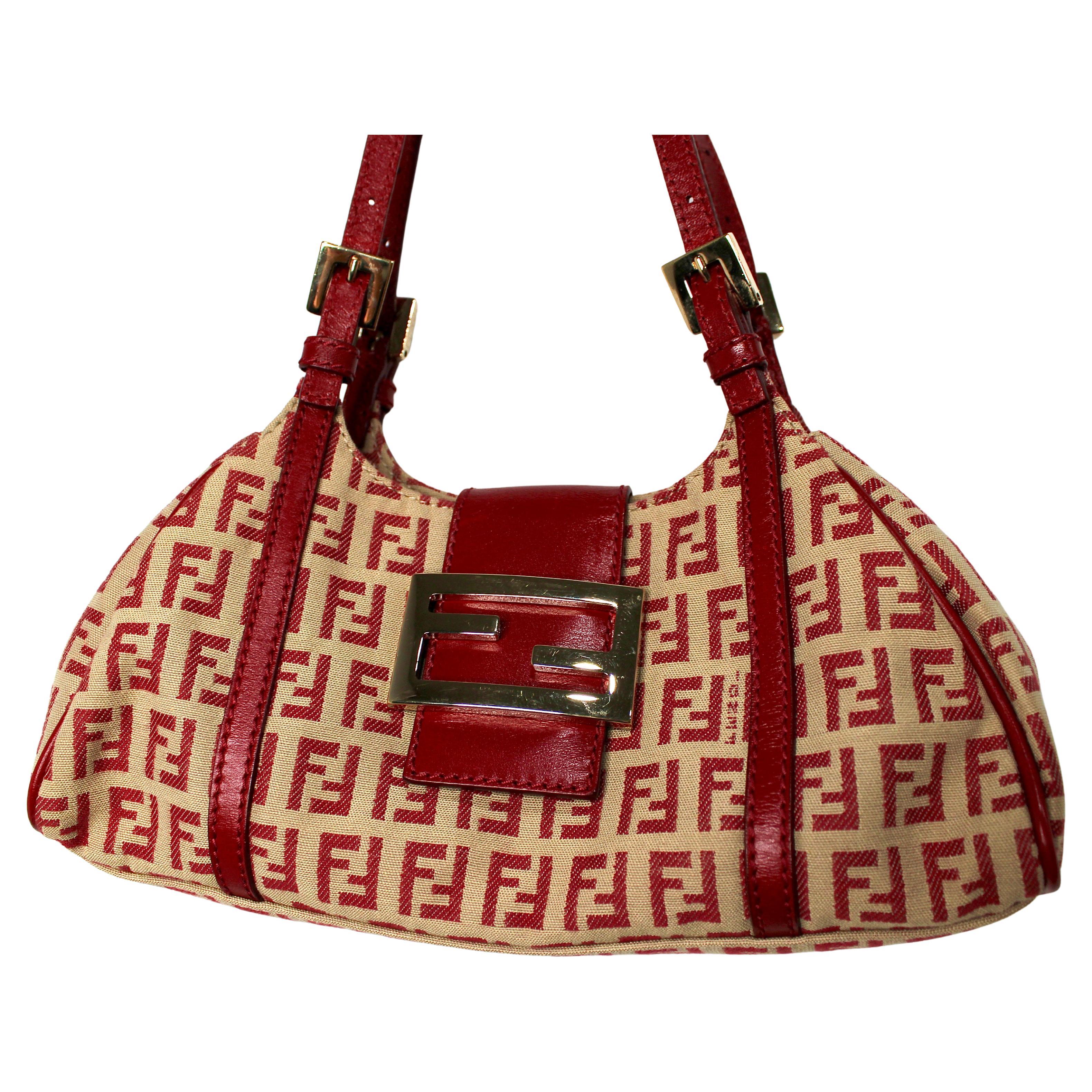 Ce sac à bandoulière iconique de Fendi en toile rouge Zucchino est la quintessence du style luxueux et ludique de l'ère Icone. Fabriquée en toile rouge de haute qualité, cette pièce est dotée d'un design audacieux et accrocheur qui ne manquera pas