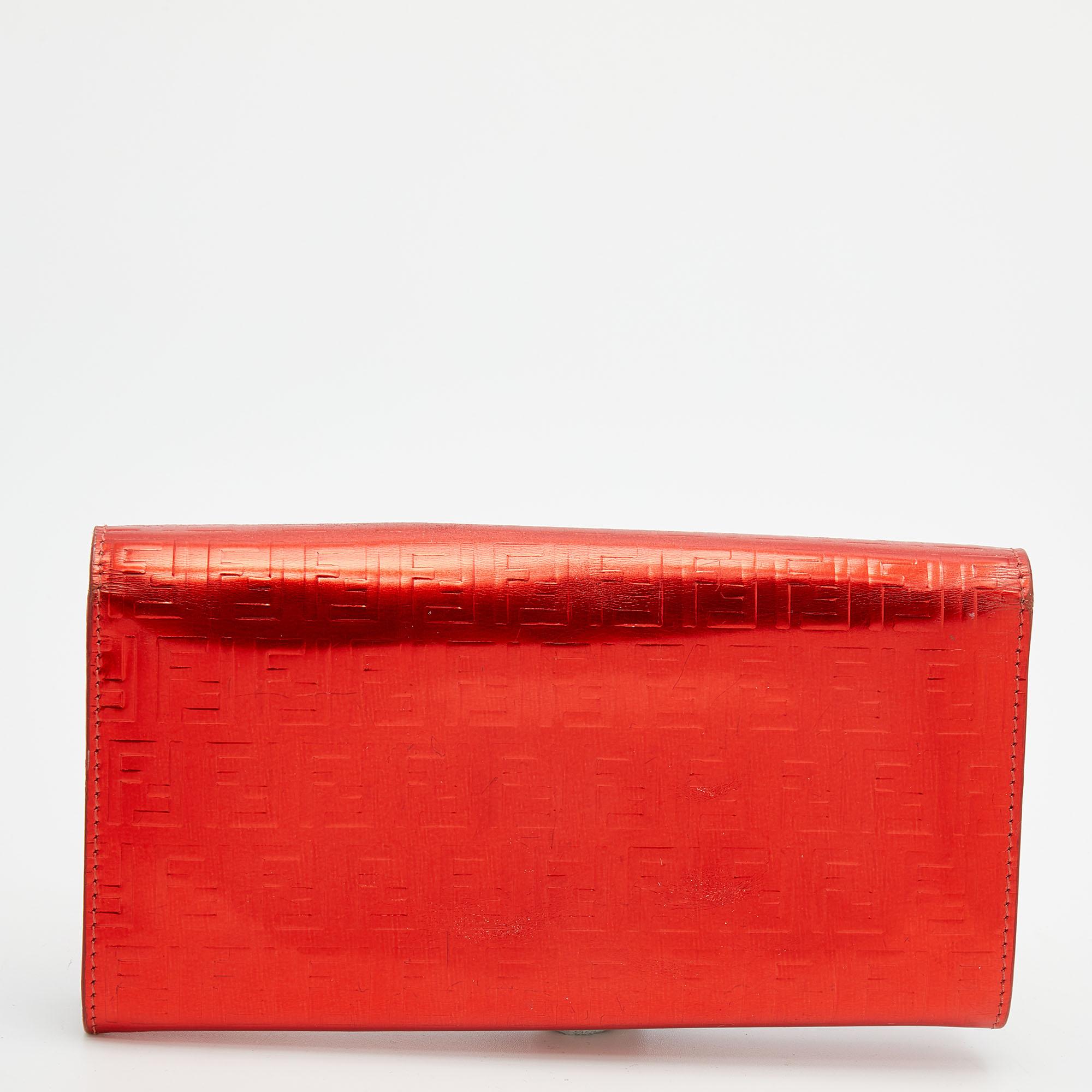 Ce portefeuille Fendi est l'hôte d'un certain nombre de détails fonctionnels. Avec un design remarquable, il est fabriqué à partir d'un cuir verni Zucchino rouge et présente une quincaillerie de couleur dorée. Son intérieur en toile et tissu enduit