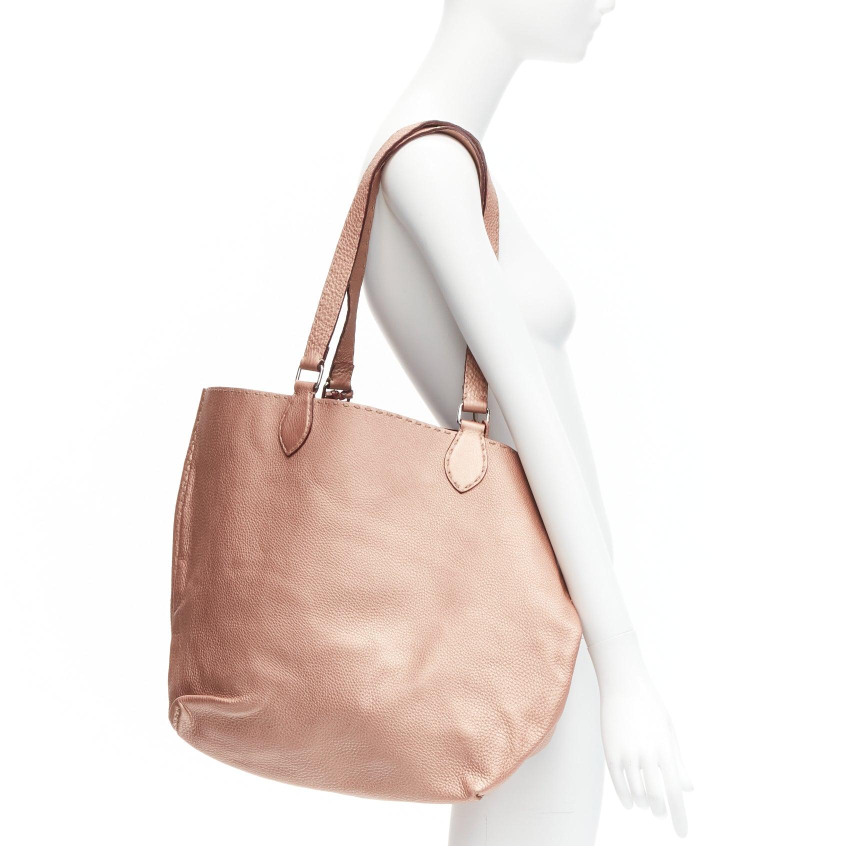 FENDI Selleria metallic rose bronze grained leather signature stitch tote bag
Reference: GIYG/A00295
Brand: Fendi
Collection: Selleria
Material: Leather
Color: Rose Gold
Pattern: Solid
Lining: Red Leather
Extra Details: Matching small pouch