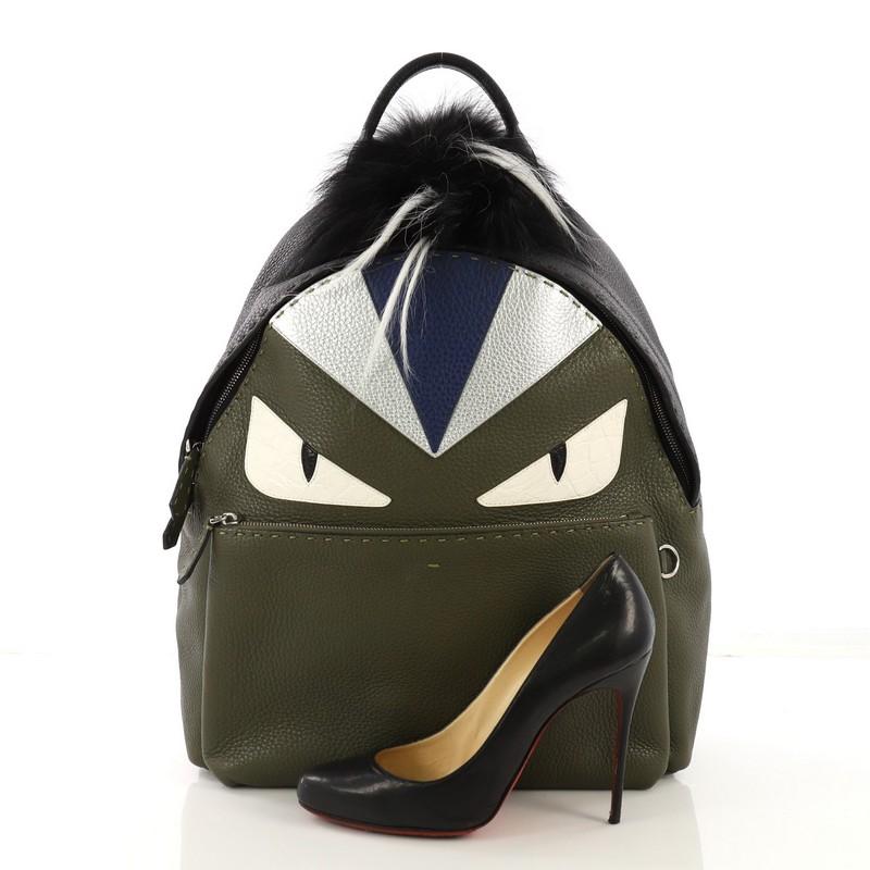 This Fendi Selleria Monster Backpack Leather and Fur Medium, crafted from green leather and black fur, features eye-catching monster eye design, a flat top handle, adjustable shoulder straps, exterior front zip pocket, and silver-tone hardware. Its