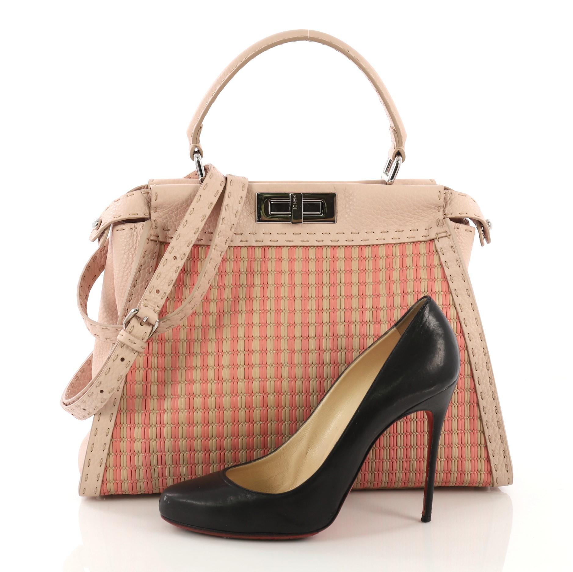 This Fendi Selleria Peekaboo Bag Woven Leather Regular, crafted from pink woven leather, features a leather top handle, frame top, protective base studs and silver-tone hardware. Its two compartments with press-lock and zip closures opens to a pink