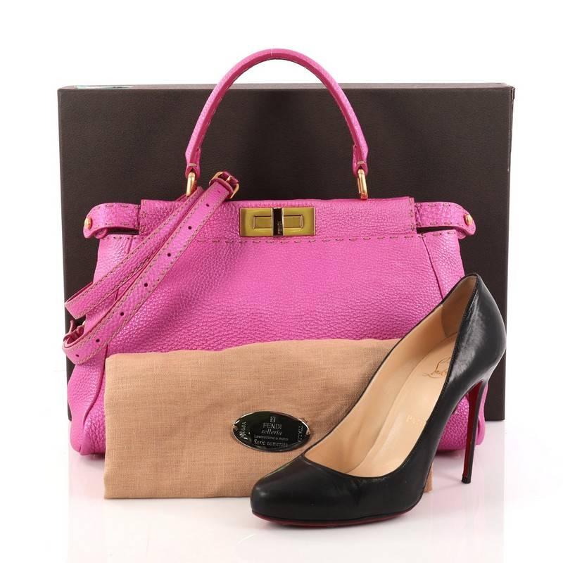 This authentic Fendi Selleria Peekaboo Handbag Leather Regular is a stand-out, carry-all piece updating its classic Peekaboo style. Crafted from luxurious metallic fuchsia leather with subtle contrast stitching, this stylish tote features a short