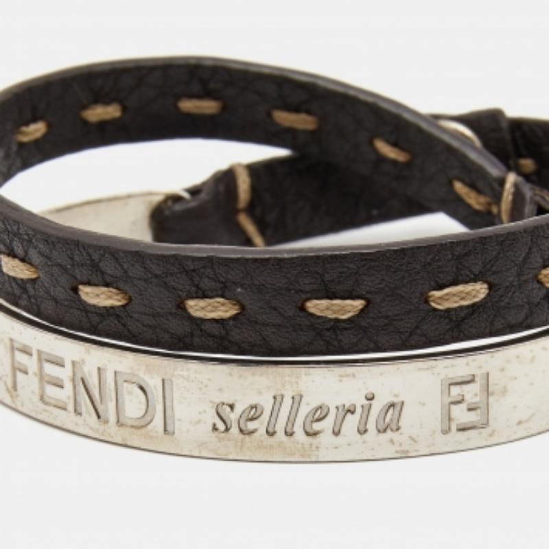 Dieses Fendi Selleria Armband wurde aus Leder gefertigt und weist ein ausgeprägtes Nahtdetail in der Mitte auf. Außerdem ist ein silberfarbener Metallarmreif angebracht, der für einen mehrschichtigen Look sorgt.