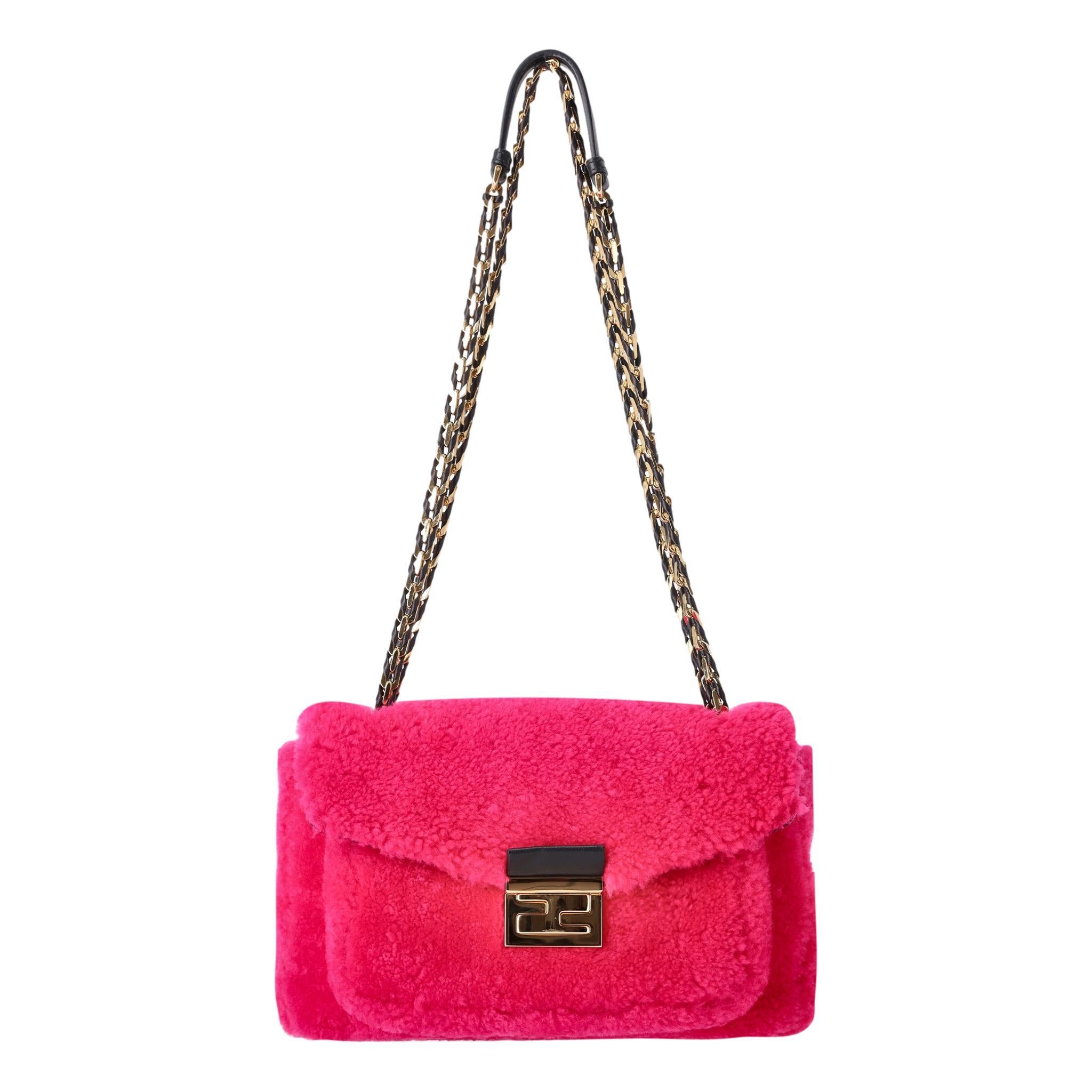 Fendi Shearling Baguette Handbag

Bright pink sheepskin bag with gold metal hardware and black leather trim.

Features a shoulder strap with polished gold chain, woven with leather.

Polished gold Fendi 'FF' closure.

Size - Height 19cm, Width 28cm,