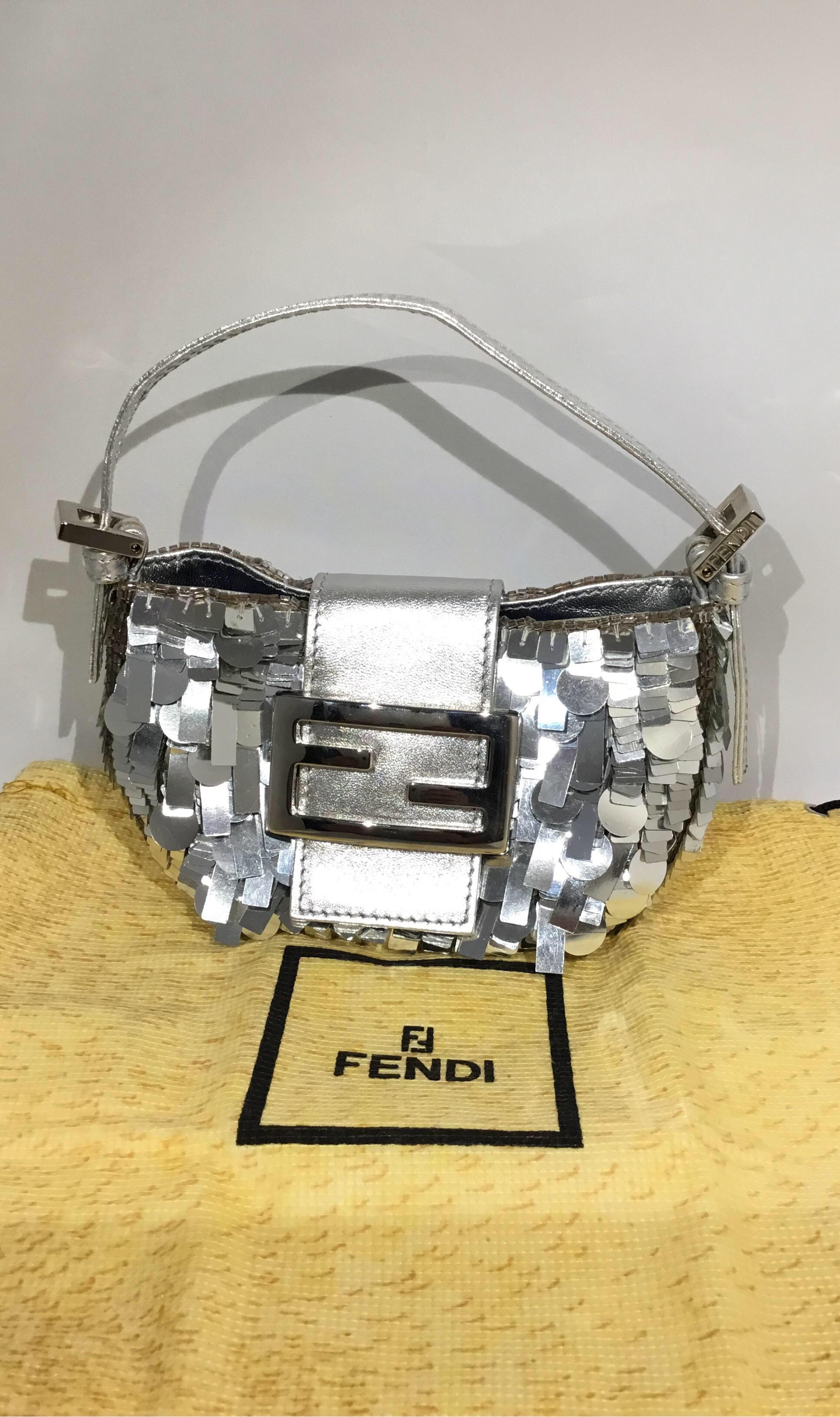 Fendi Mini baguette featured in silver with a fully sequined detail and bead trim along the opening and frame of the Purse. There is a flat leather top handle attached with silvertone hardware and a signature Fendi flap-snap closure. Bag has a