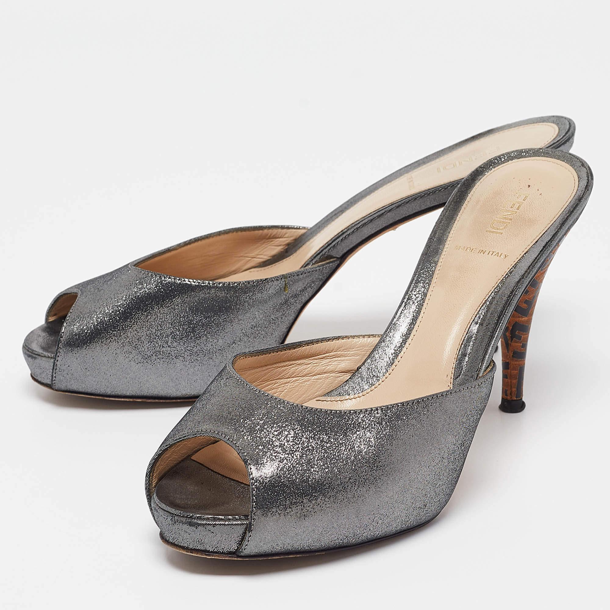 These Fendi slide sandals will offer you both luxury and comfort. Made from quality materials they come in a silver hue and are lifted on Zucca heels.