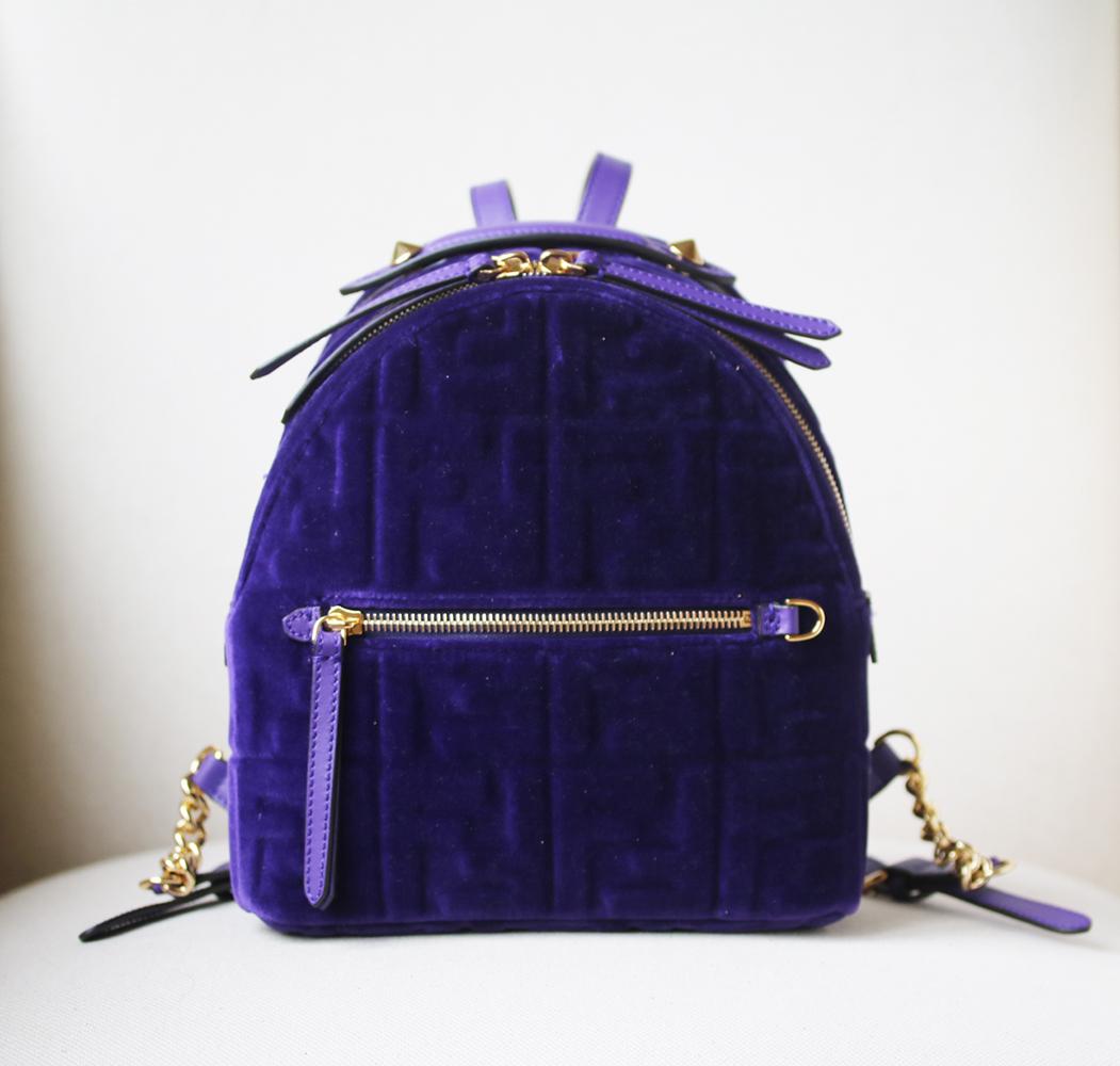 Mini backpack with zip fastening and front pocket. Inside there is an additional zip pocket. Thin, adjustable handle and shoulder straps with a chain insert.  Made of purple velvet with embossed FF motif. Details in leather. Gold-finish metalware.