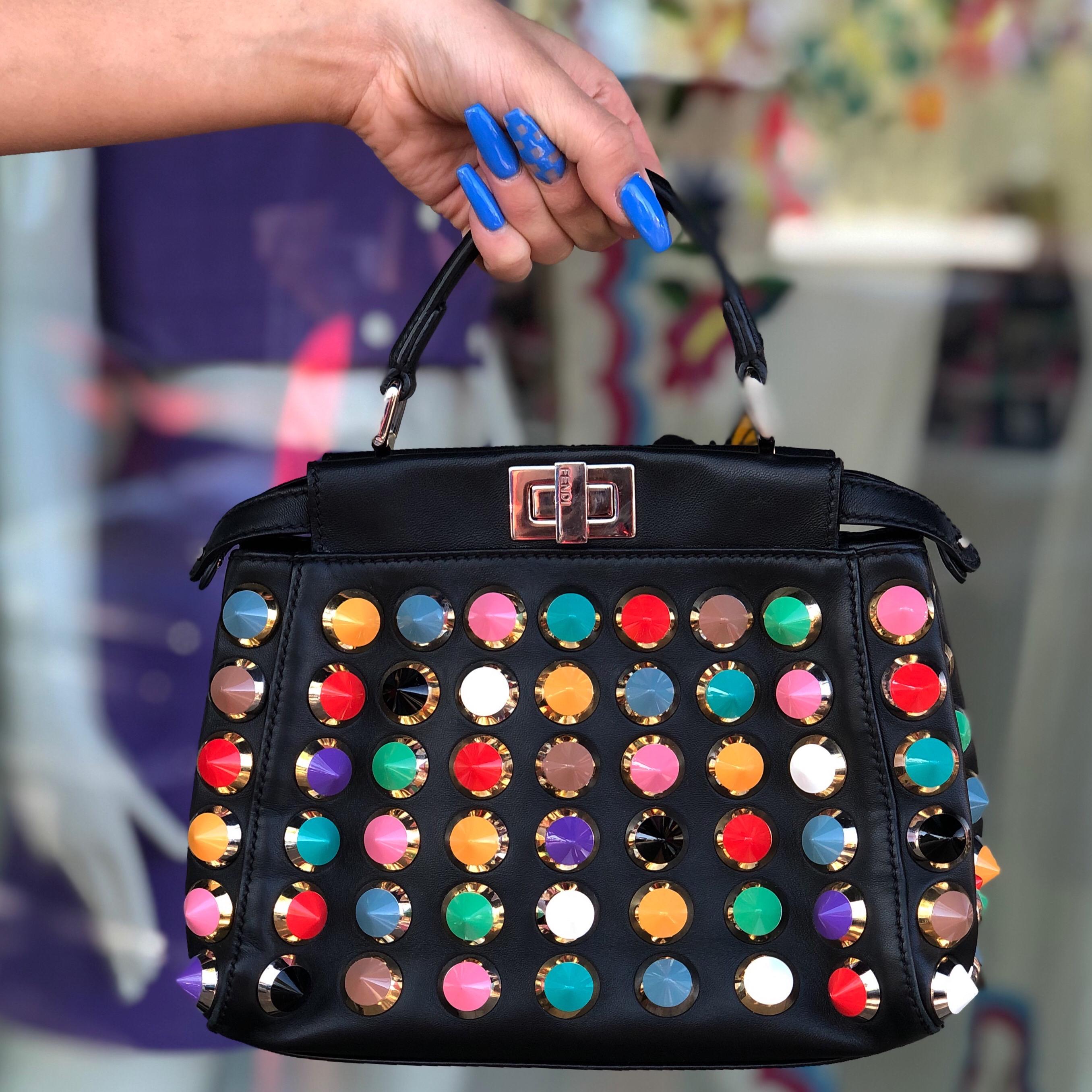 Add some color to your look with this amazing Fendi! Circa 2015, this coveted peek-a-boo bag is crafted from black leather and features a colorful studded exterior, silver turn lock closure, single flap top handle and a detachable shoulder strap.