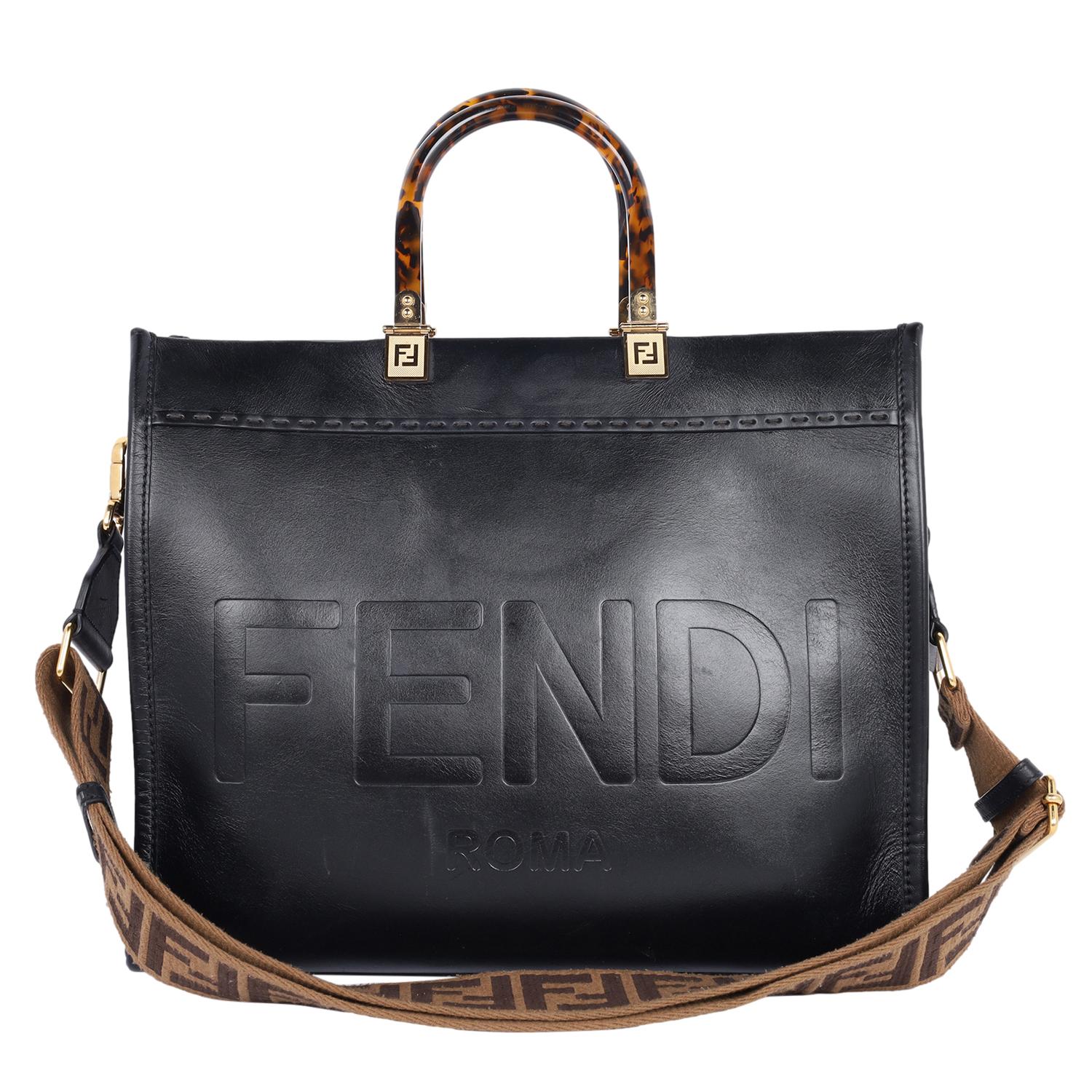 Authentic, pre-loved Fendi Sunshine Shopper bag made of black leather with hot-stamped “FENDI ROMA” and stiff tortoise shell plexiglass handles. Features a very large internal compartment, tone on tone leather edges and gold-finish metalware.

Can