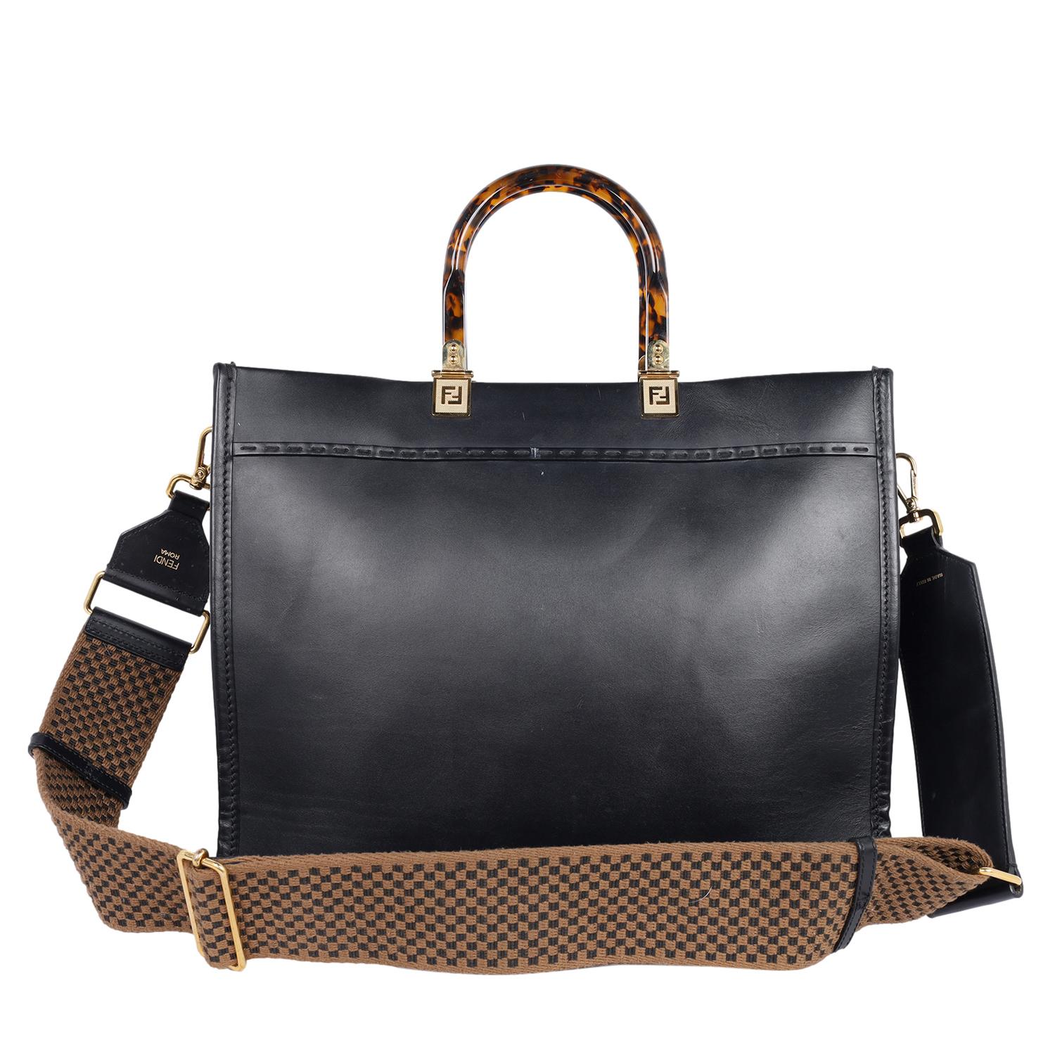 Authentic, pre-owned Fendi Sunshine Shopper bag. Features black leather with hot-stamped “FENDI ROMA” and stiff tortoise shell plexiglass handles. Features a very large internal compartment, tone on tone leather edges and gold-finish metalware.

Can